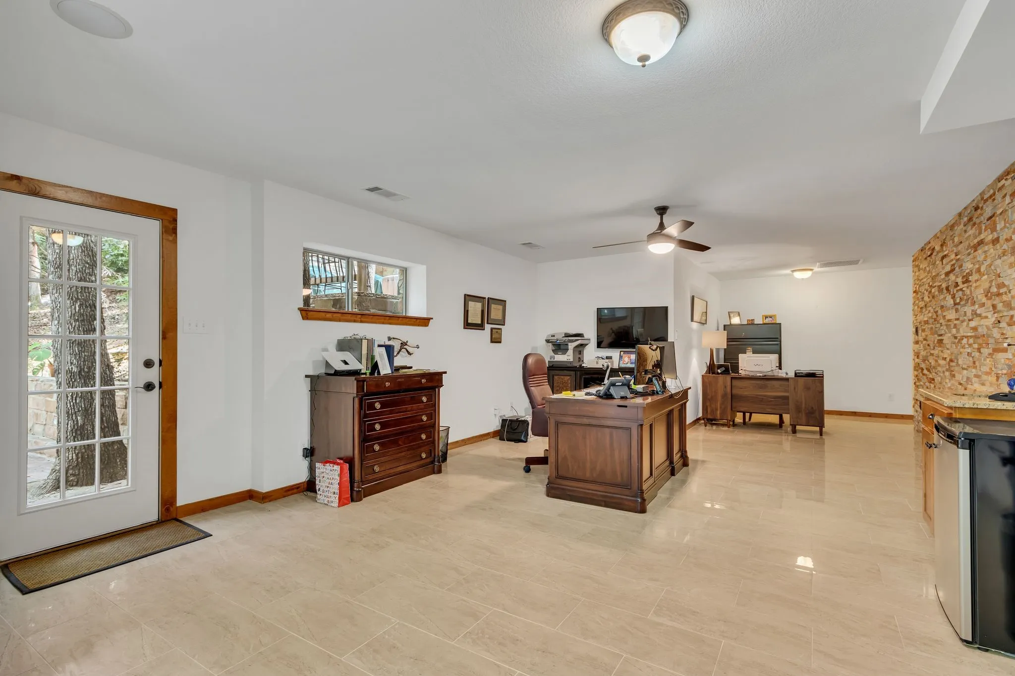 Spacious multi-purpose room featuring light-toned tile flooring, white walls, and warm wood trim