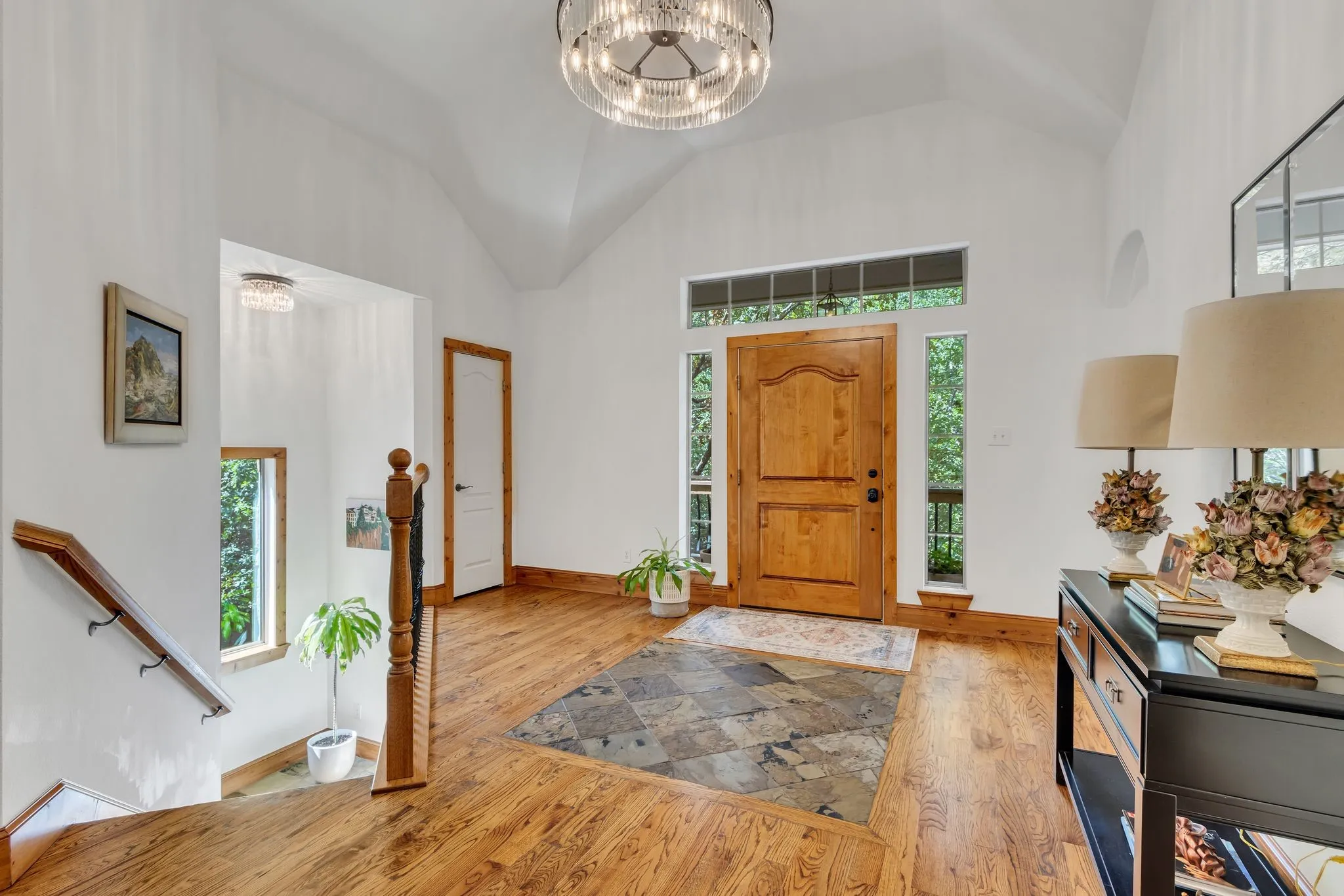 Vaulted entry featuring a wood-finish front door with sidelight windows, a transom window, and a central tile inlay