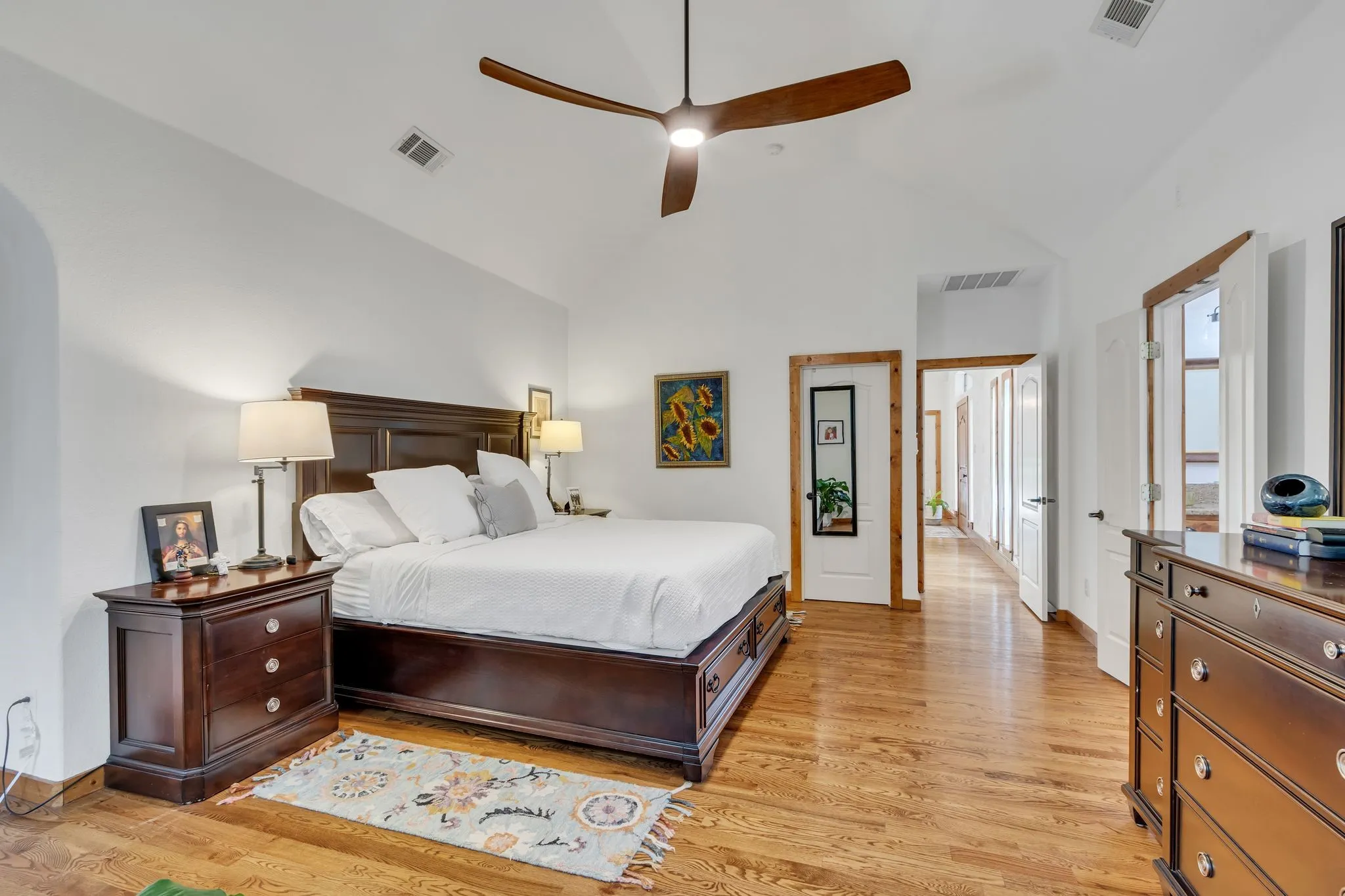 Vaulted ceiling bedroom featuring wood-finish flooring, a contemporary ceiling fan, and white​​‌​​​​‌​​‌‌​‌‌​​​‌‌​‌​‌​‌​​​‌​​ walls