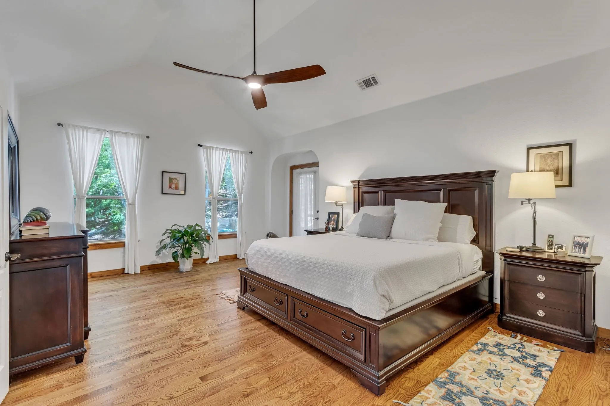 Spacious bedroom featuring vaulted ceilings, light wood-finish flooring, and multiple windows