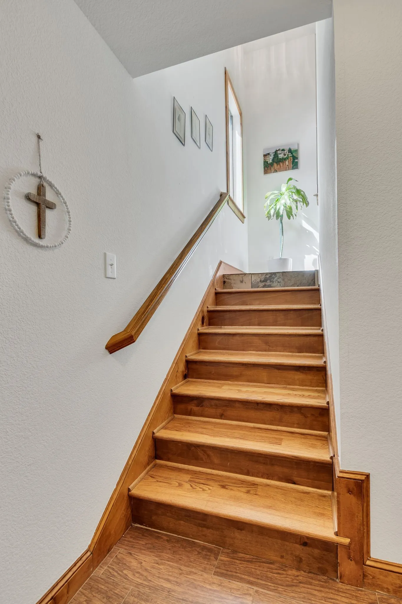 Hardwood staircase featuring a wood handrail and matching wood-finish flooring