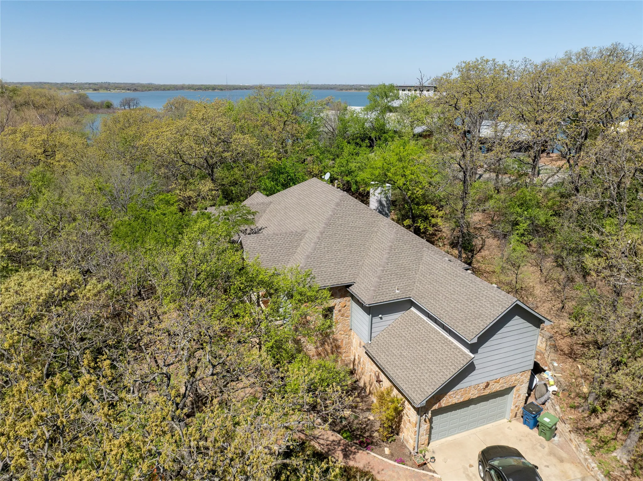 Multi-level residence featuring a shingle roof and a combination of stone and siding exterior finishes