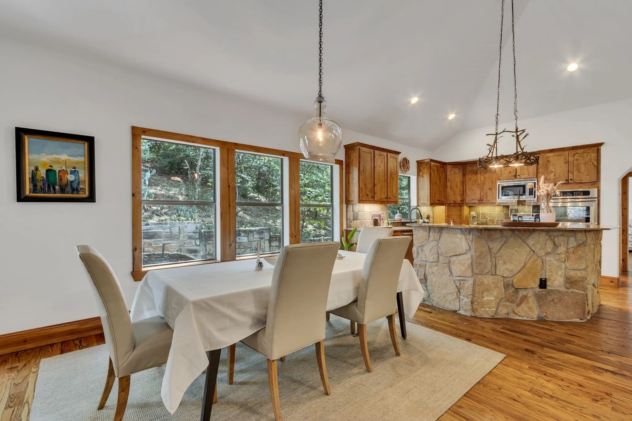 Open-concept dining area featuring wood-finish flooring, a vaulted ceiling, and recessed lighting