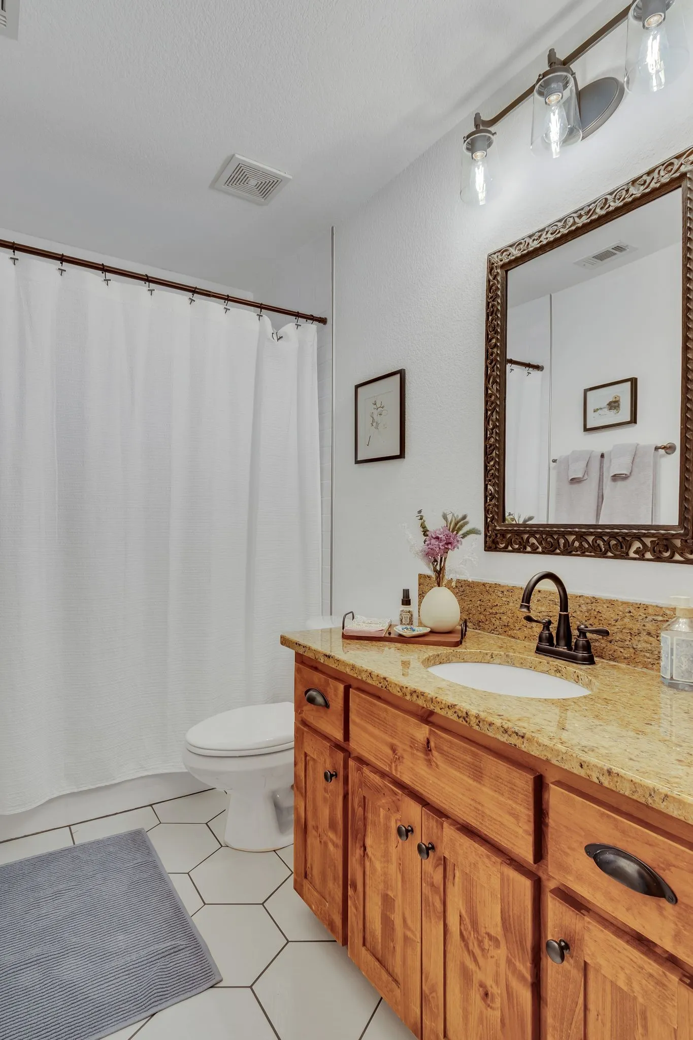 Bathroom featuring a wood vanity with a stone countertop, an undermount sink, and a dark bronze faucet