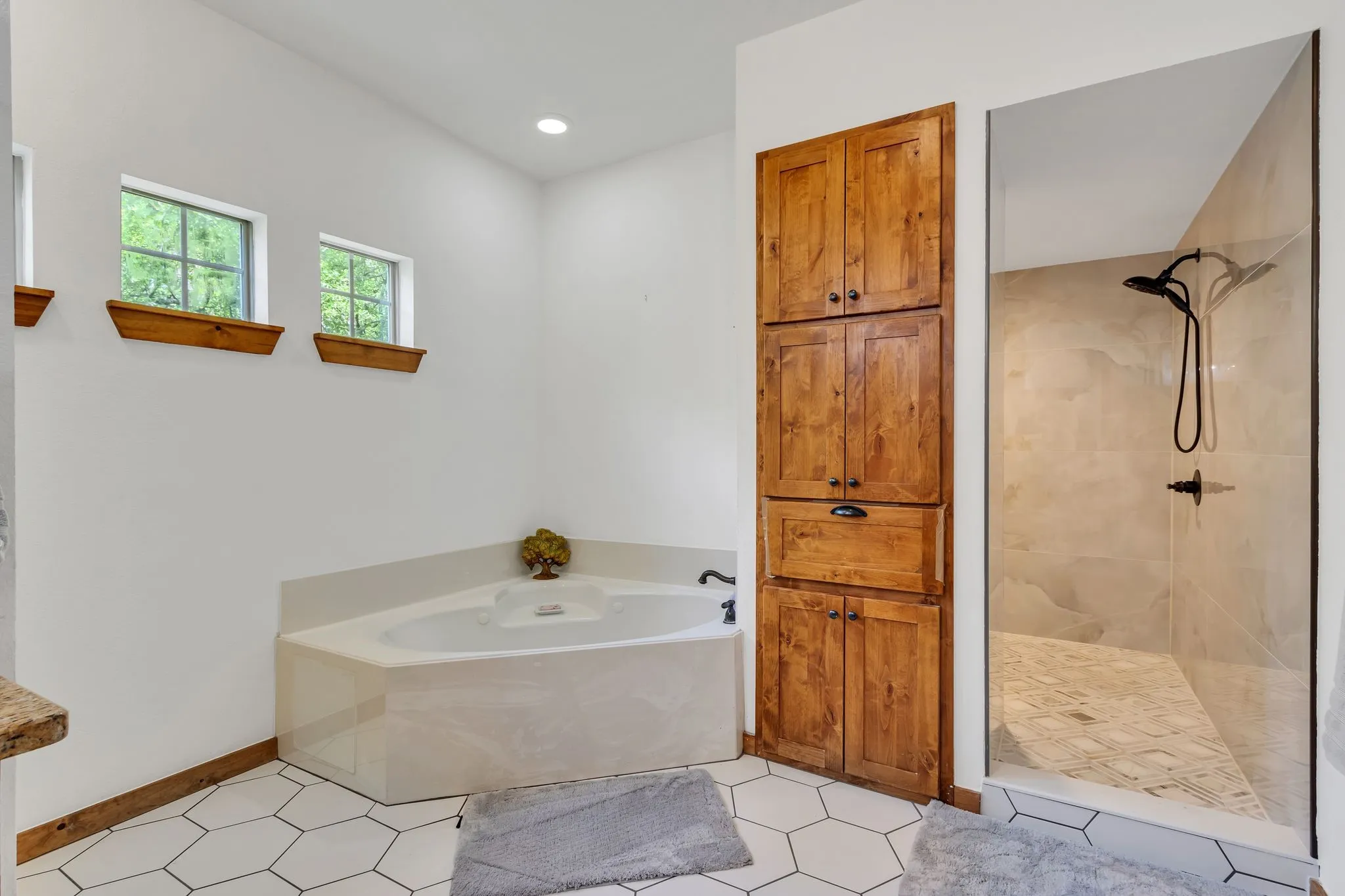 Enclosed shower with dark fixtures and light-toned tile, featuring a built-in wooden storage cabinet