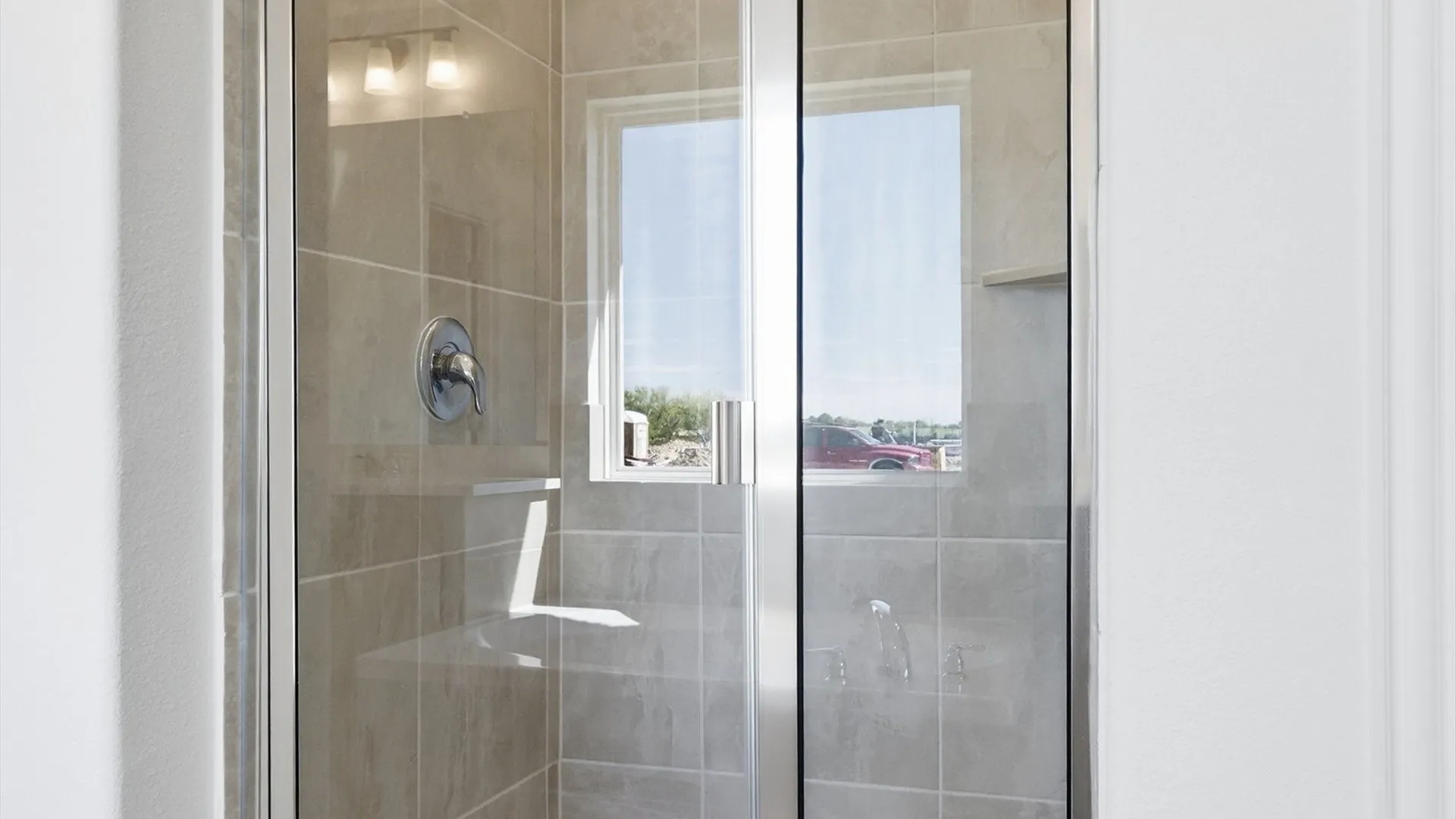 Glass-enclosed shower with tile surround and integrated shelving
