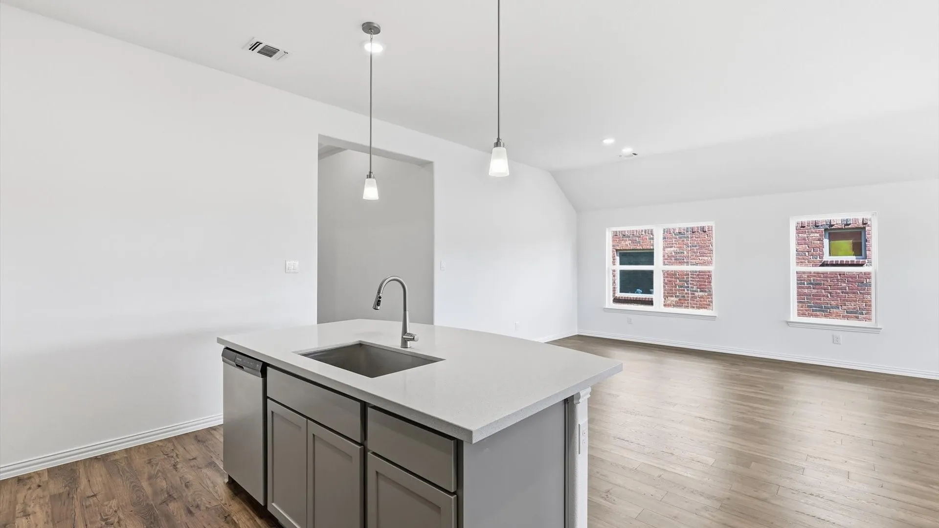 Kitchen island featuring a stainless steel undermount sink, a stainless steel dishwasher, and pendant lighting