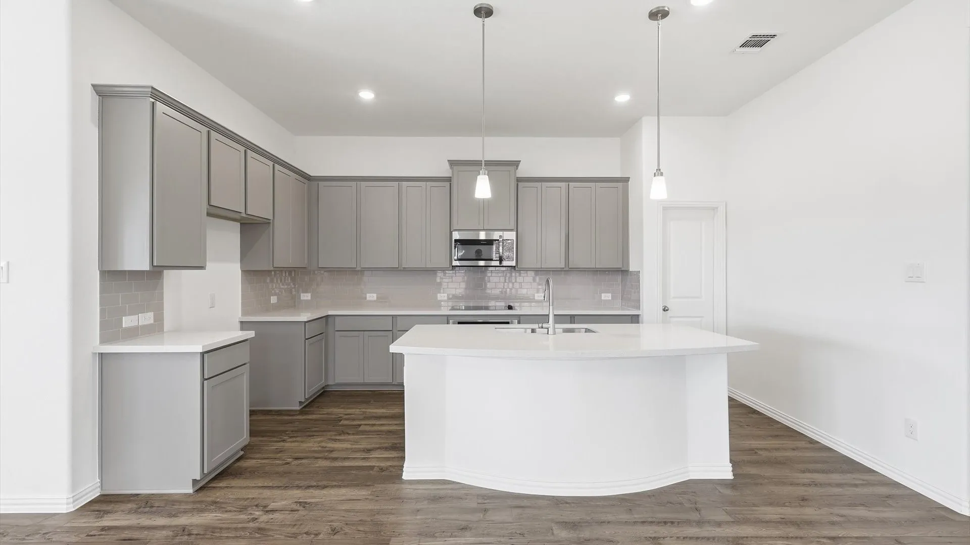 Modern kitchen featuring light gray cabinetry, white countertops, a mosaic tile backsplash, stainless steel appliances, and a central island with pendant lighting