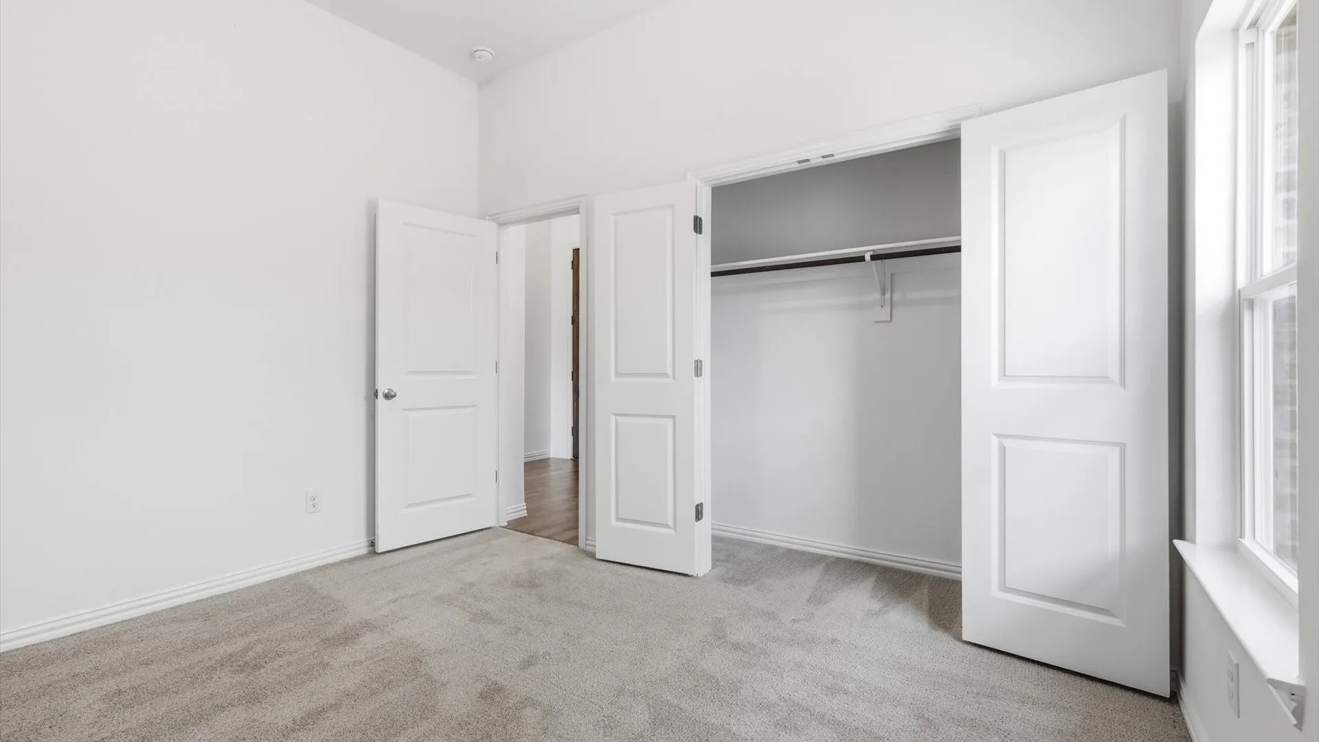 Room featuring light gray carpeting, white walls, and a window with white trim