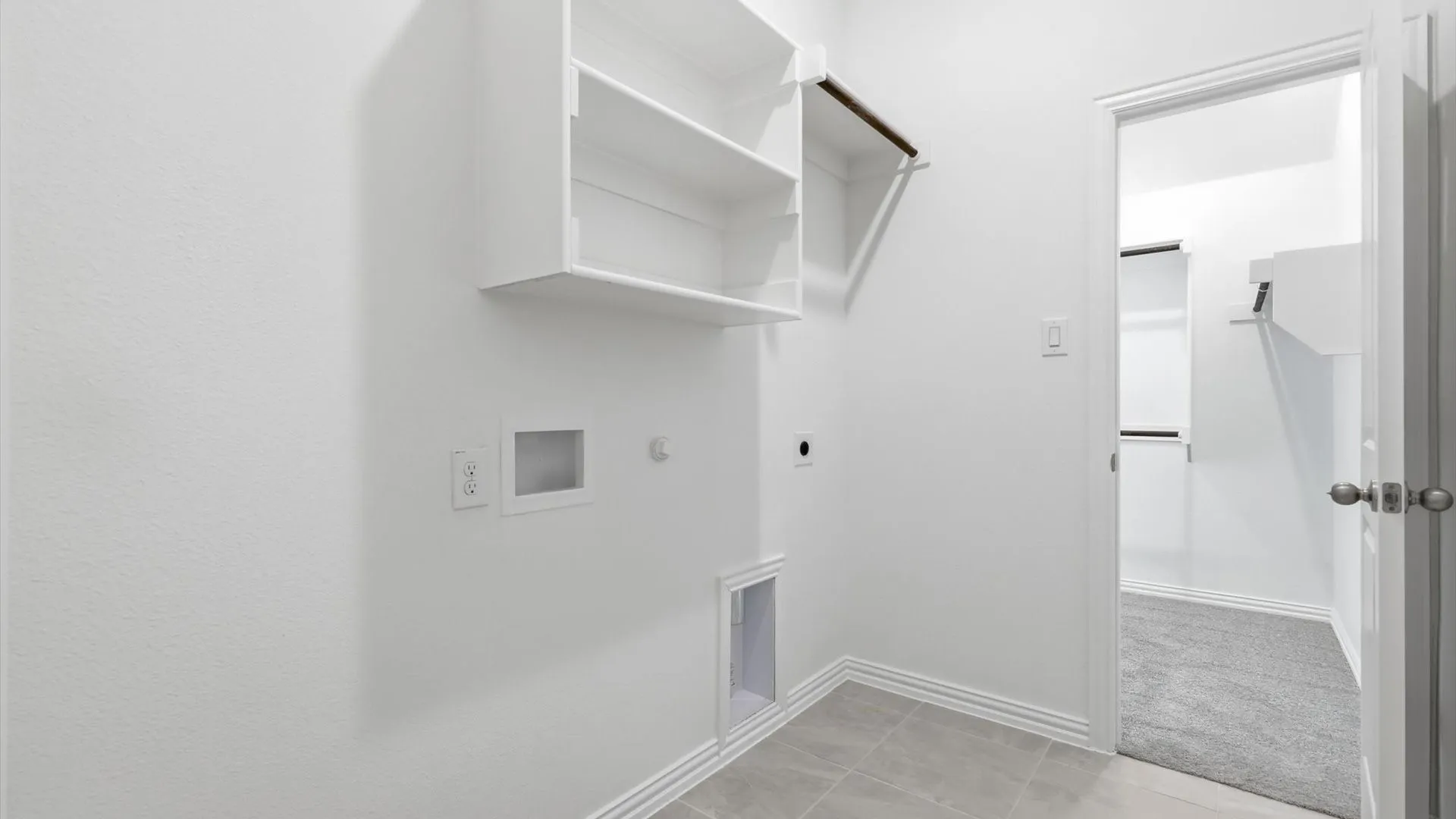 Laundry area featuring built-in shelving, a clothes hanging rod, tile flooring, and white baseboards