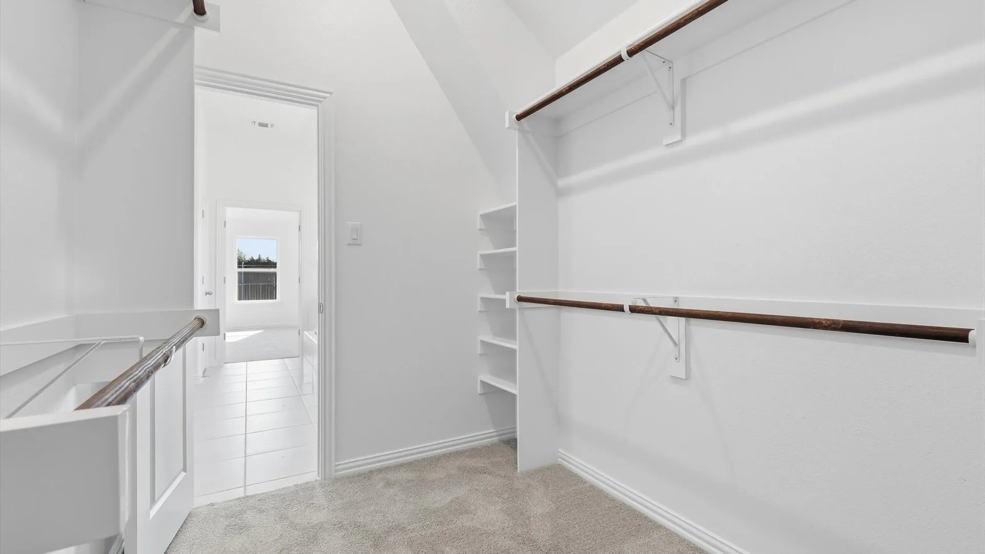 Expansive closet space featuring plush carpet flooring, multiple shelving units, and two levels of hanging rods