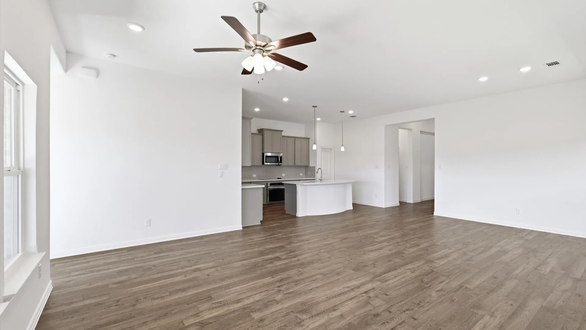 Spacious open-concept living area featuring wood-finish flooring, recessed lighting, and a ceiling fan