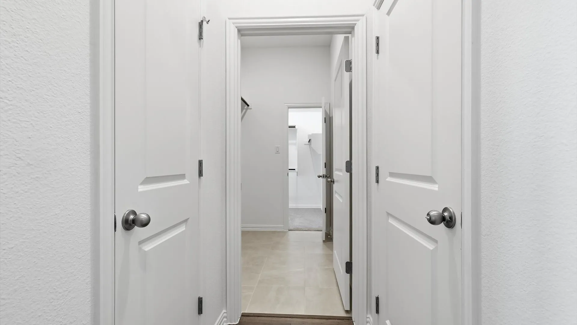 Hallway featuring multiple white paneled doors with satin nickel hardware
