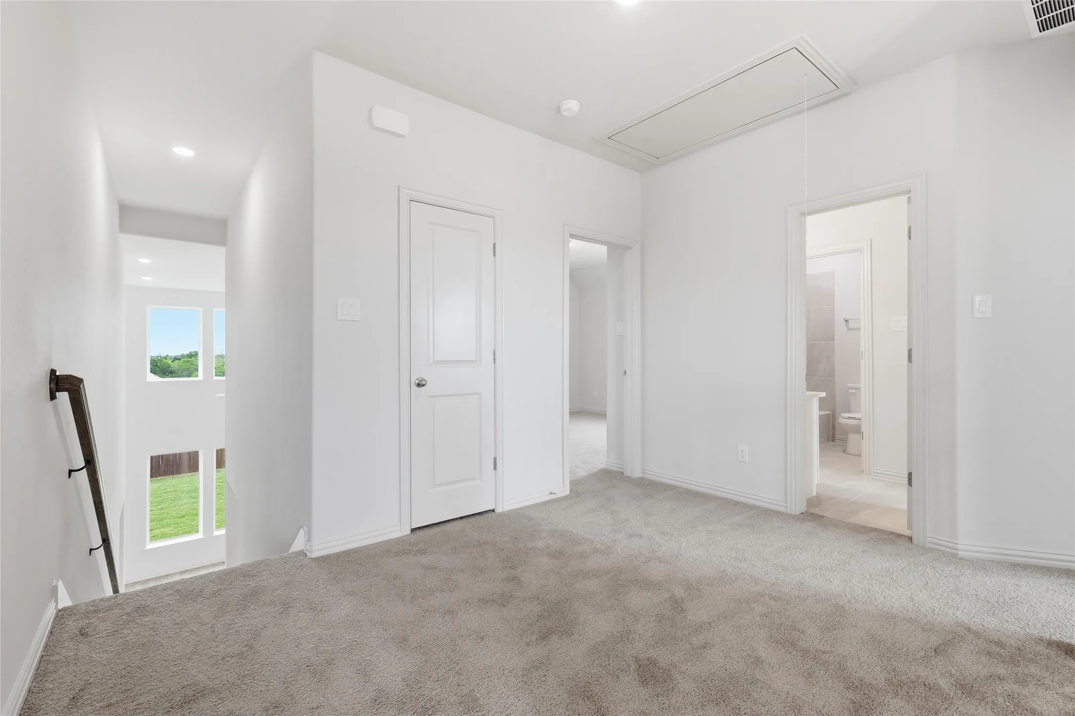 Open upstairs landing featuring neutral-toned carpeting, white walls, and bright recessed lighting