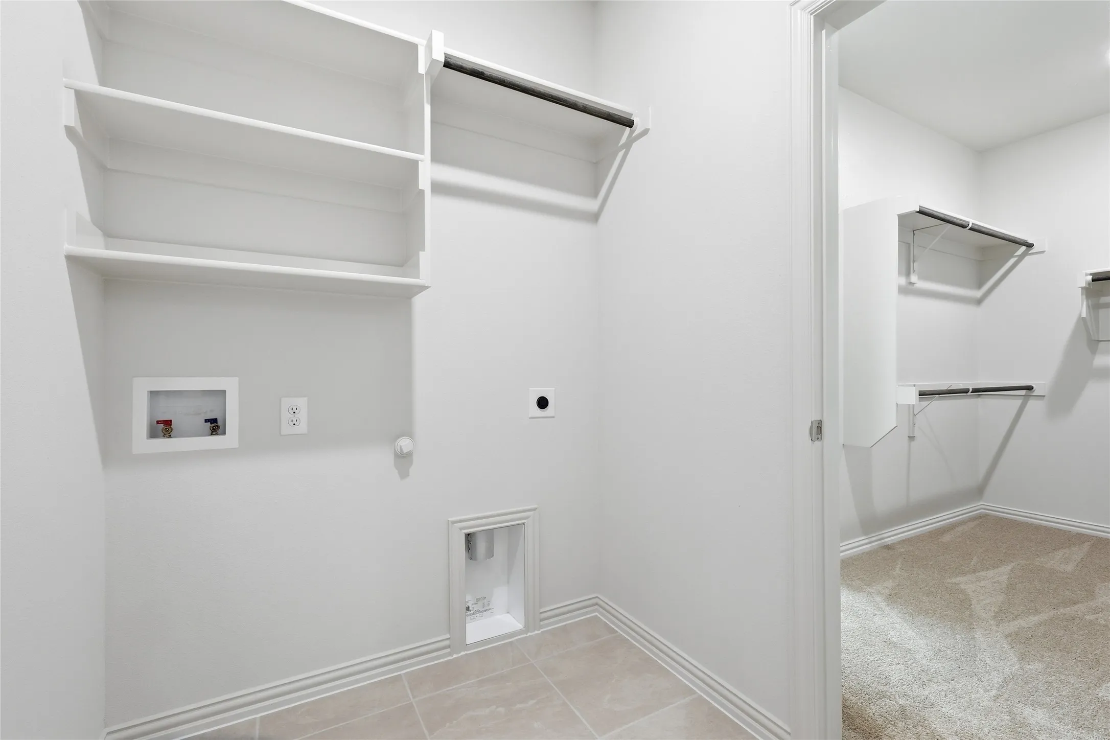 Dedicated utility area with tiled flooring, integrated shelving, and clothing rod