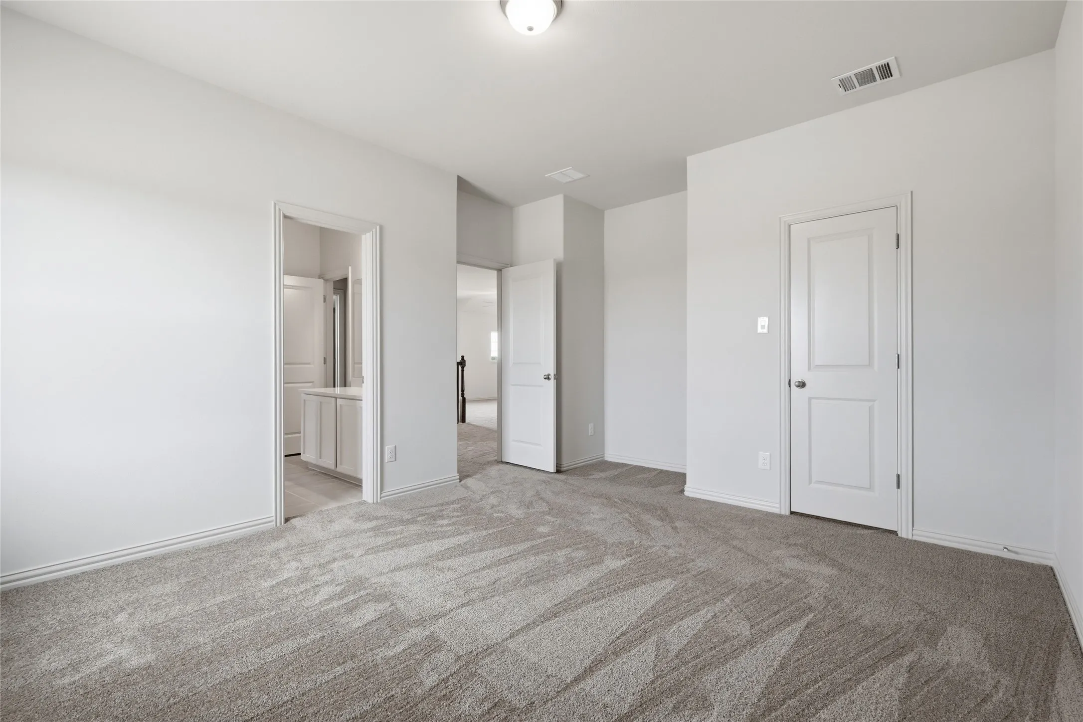Spacious room with light gray patterned carpet and white walls