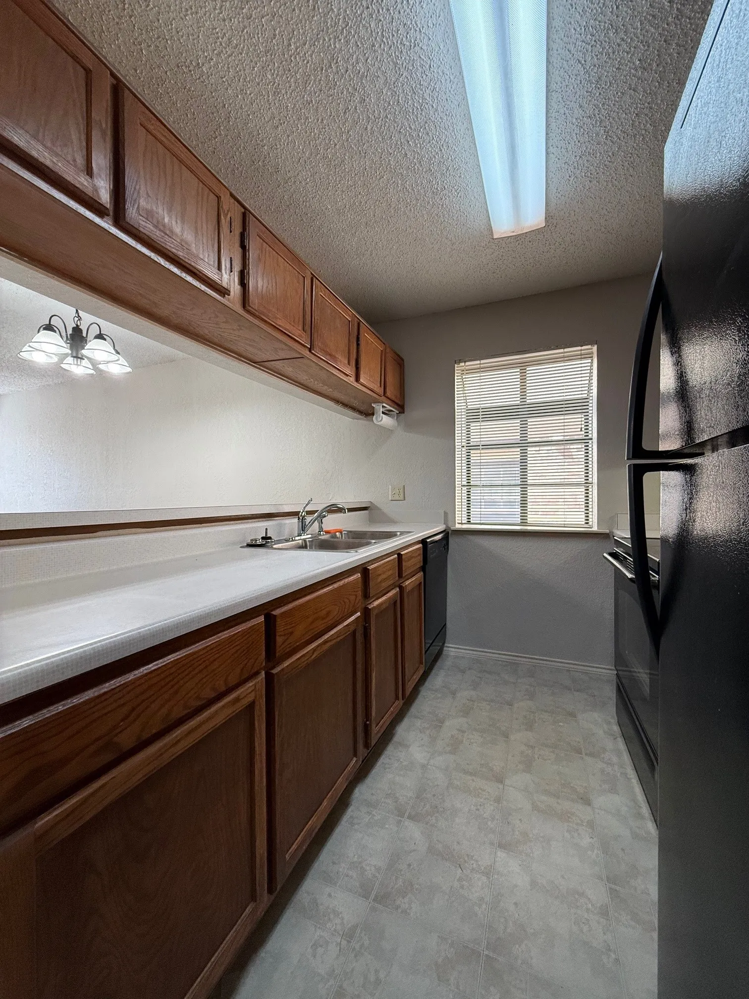 Kitchen featuring light countertops, a textured ceiling, and black appliances