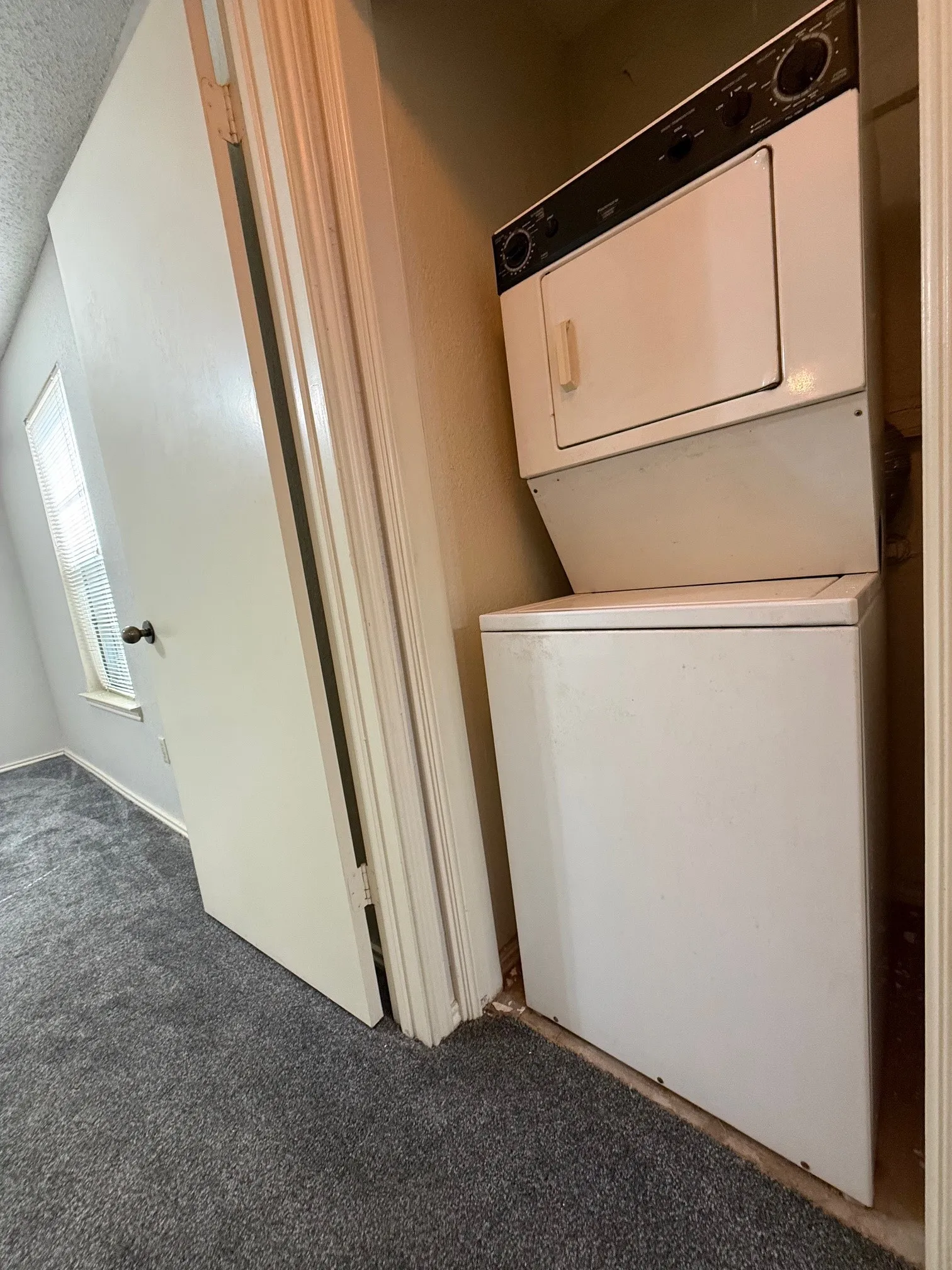 Laundry area featuring carpet floors, stacked washer and dryer, and a textured ceiling