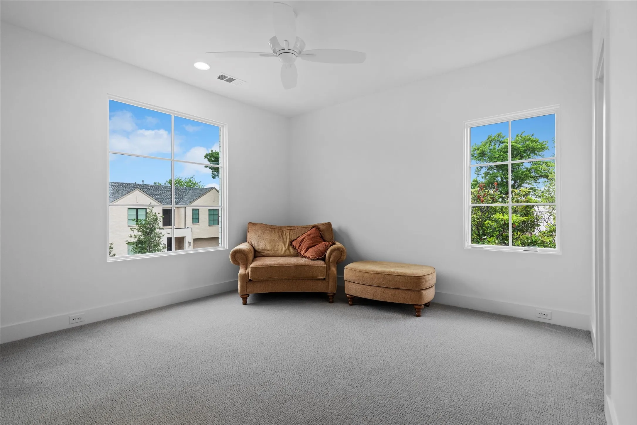 Third secondary bedroom with a wealth of natural light, dark carpet, and ceiling fan.