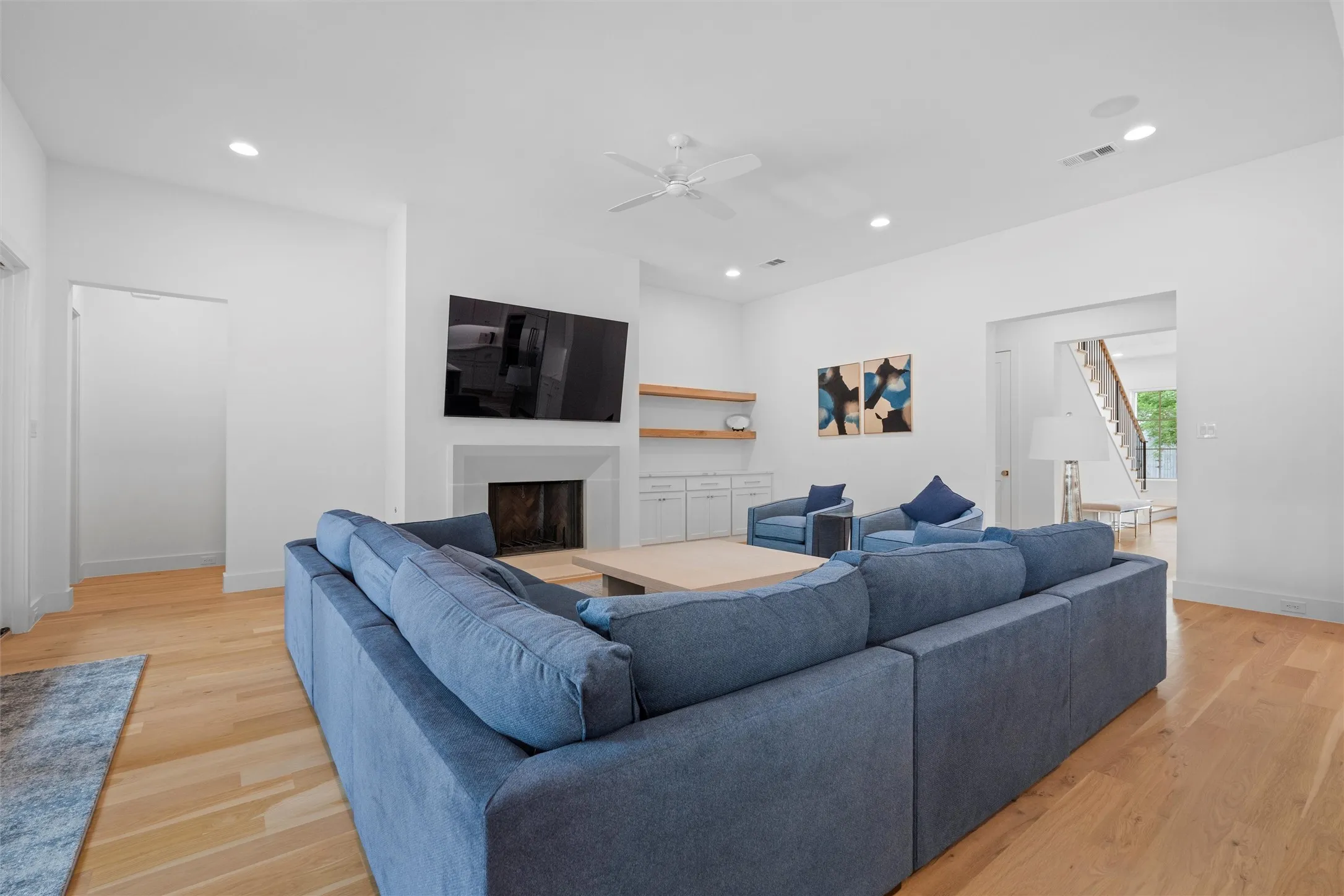 Living room featuring light hardwood / wood-style floors, gas logs in cozy fireplace, and ceiling fan.
