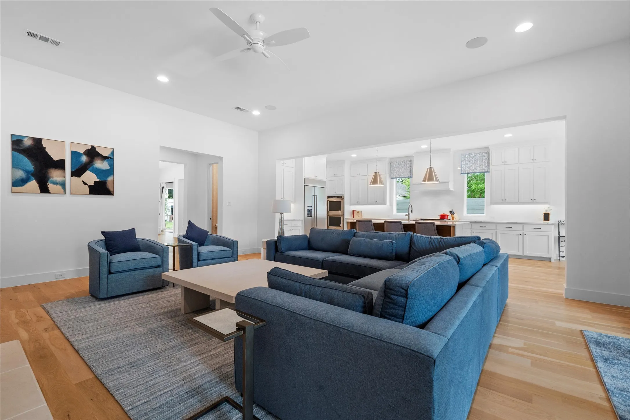 Living room open to kitchen area, featuring ceiling fan, and light wood-type flooring