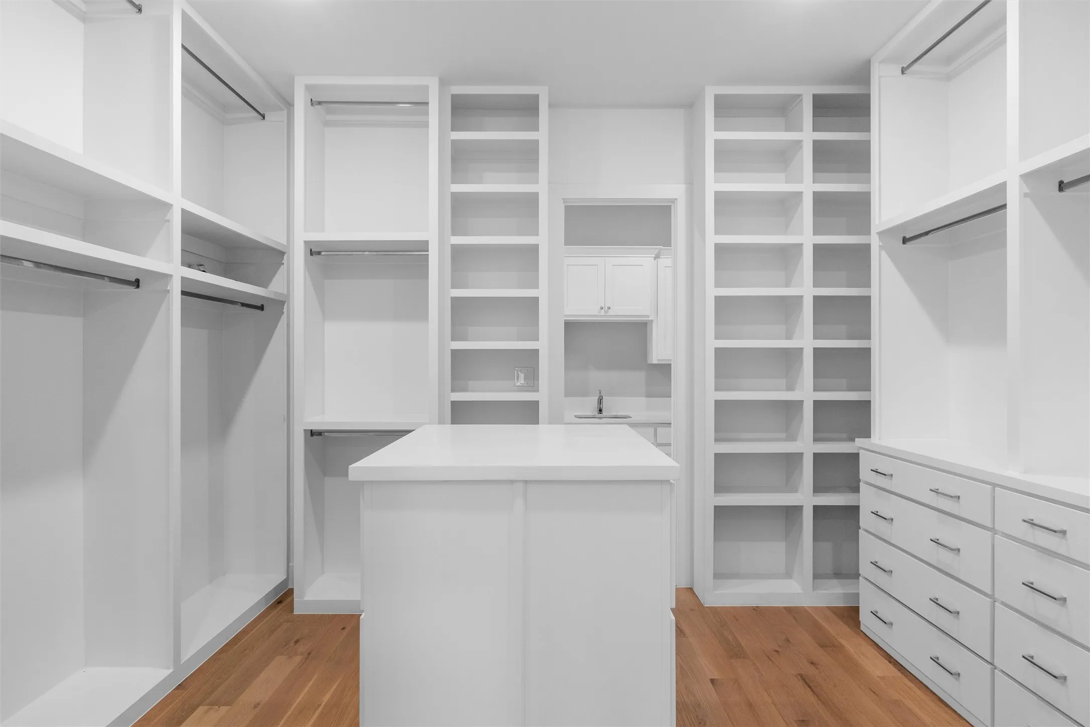 Walk in master closet with light hardwood / wood-style flooring and extensive storage!