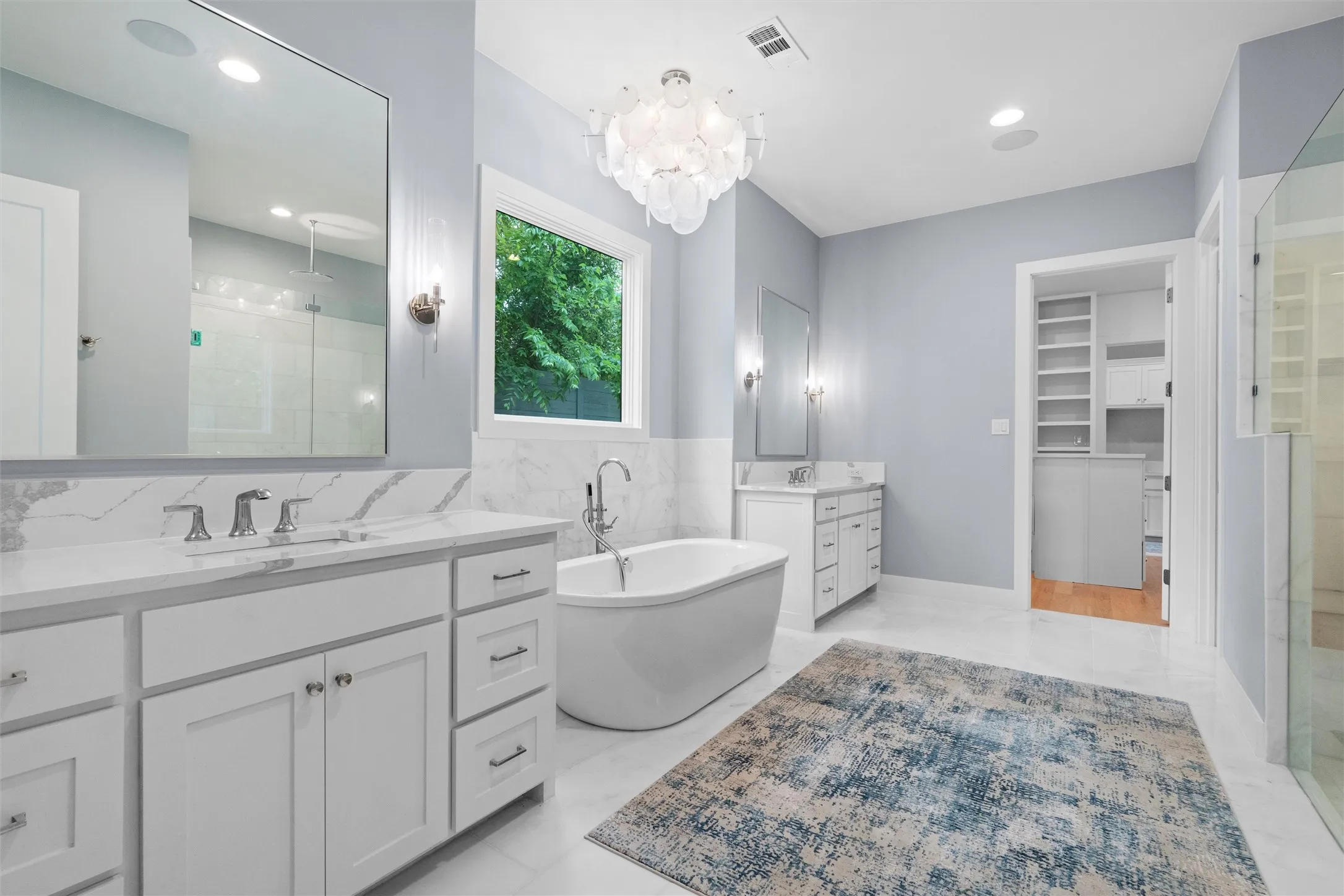 Master bathroom with marble floors, extra large shower with marble shower walls, double vanities, a notable chandelier, and independent shower and bath.