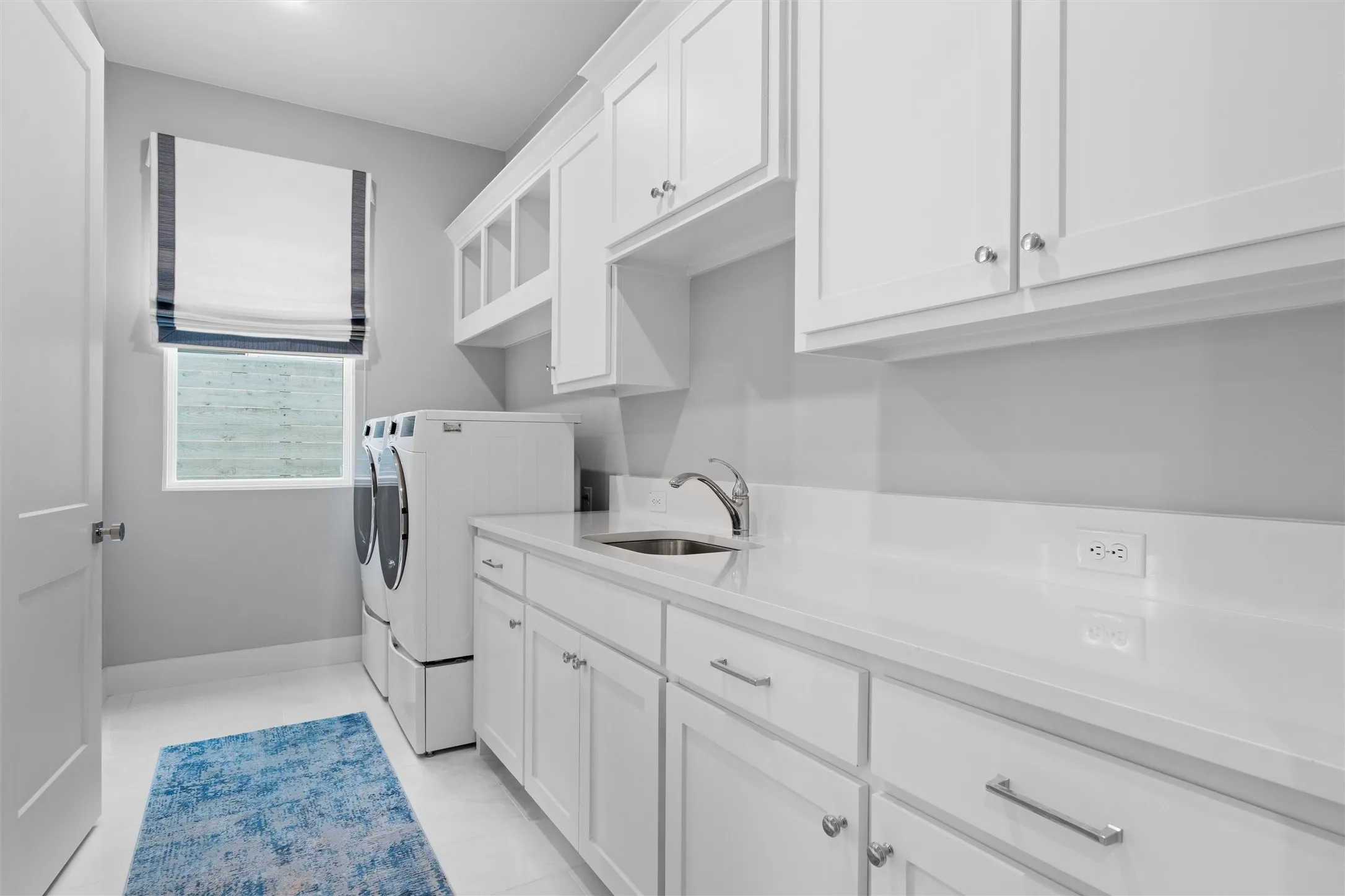 Conveniently located beyond the master closet, utility room features cabinets, sink, marble  floors, and room for full size washing machine and clothes dryer.
