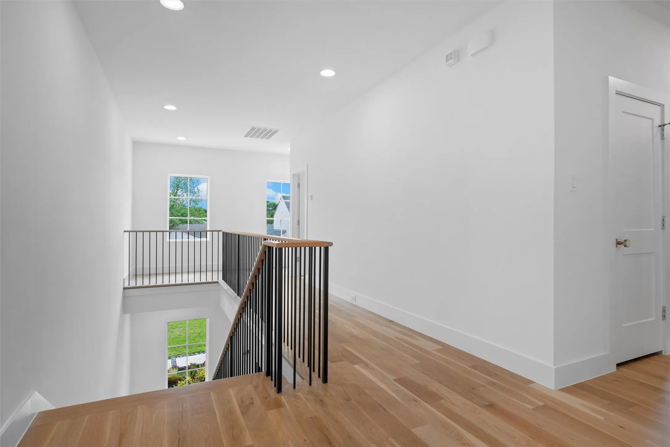 Second floor landing, leading to bedrooms, game room and exercise room.  Corridor with plenty of natural light and light wood-type flooring.
