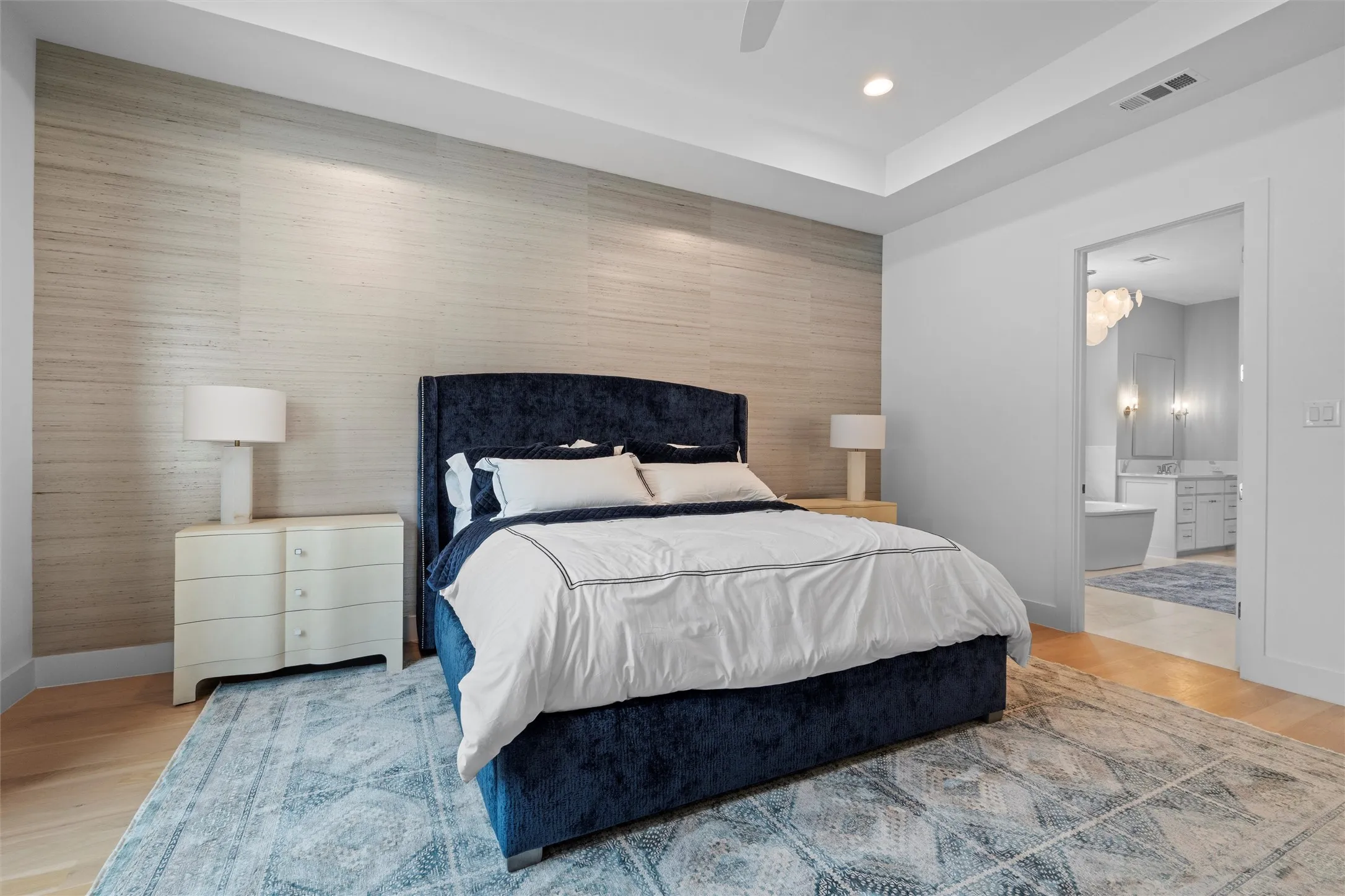 Master bedroom featuring ceiling fan, ensuite master bathroom, and light wood flooring.