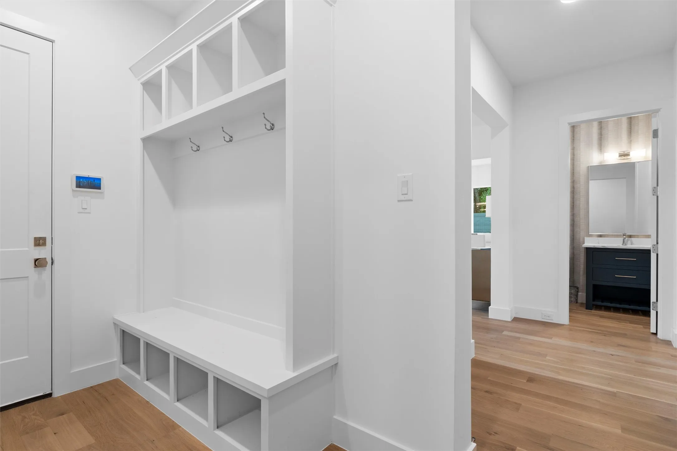 Mudroom featuring light wood-style floors and plenty of cubbies and hangers for shoes, backpacks and coats.