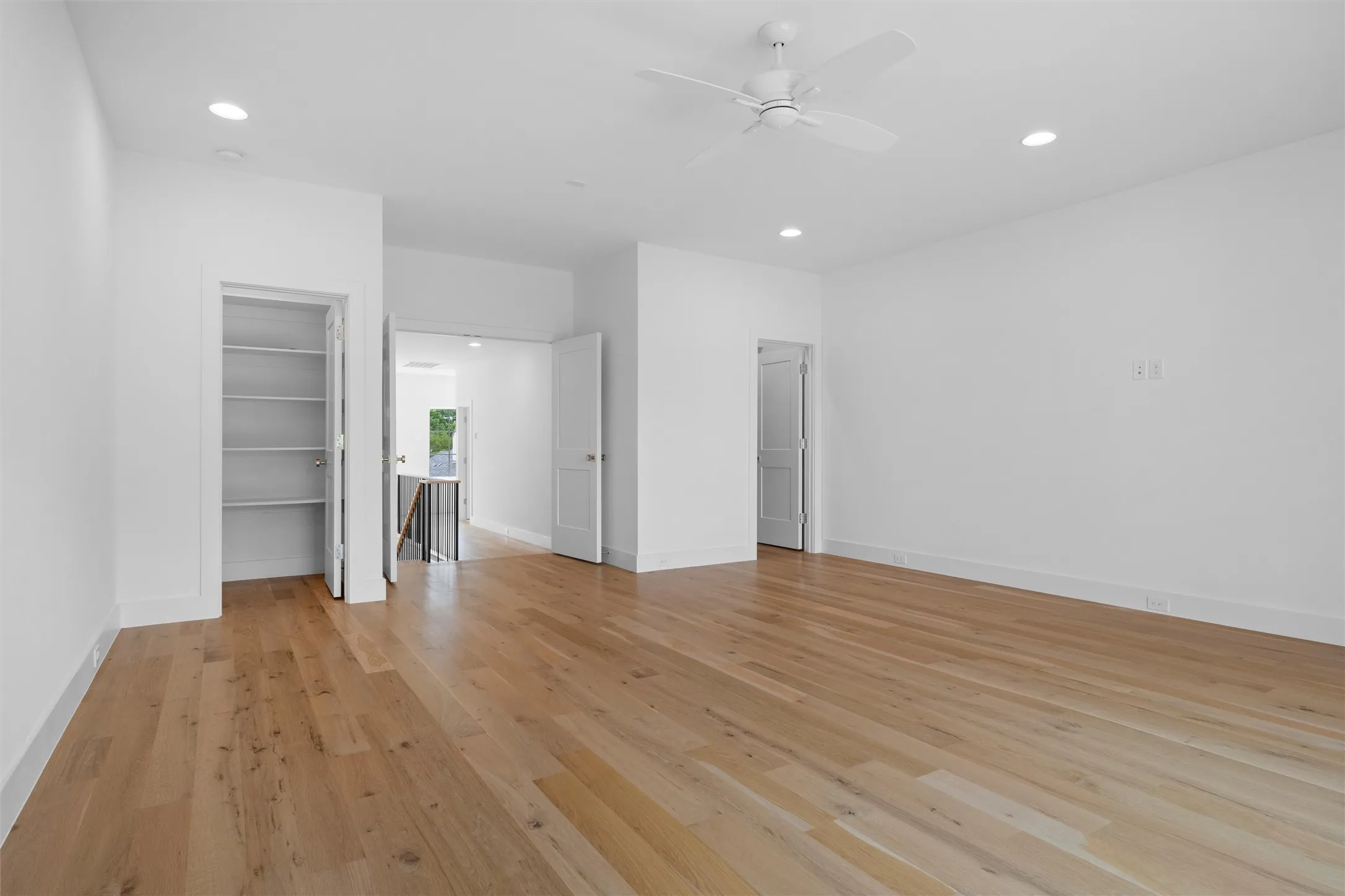Another view of the large game room featuring ceiling fan, two walk in closets, and light hardwood / wood-style floors.