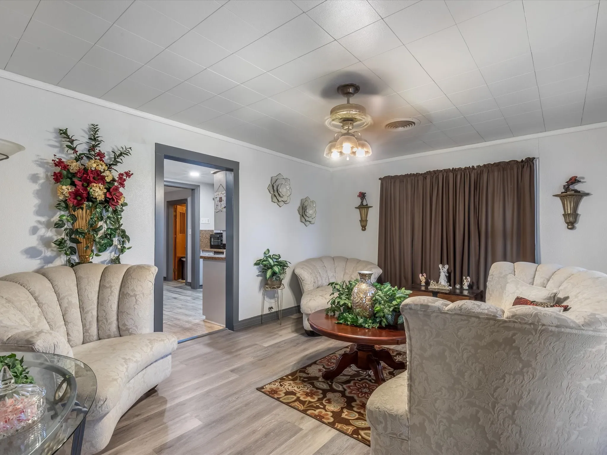 Living room featuring wood finished floors, a ceiling fan, and crown molding