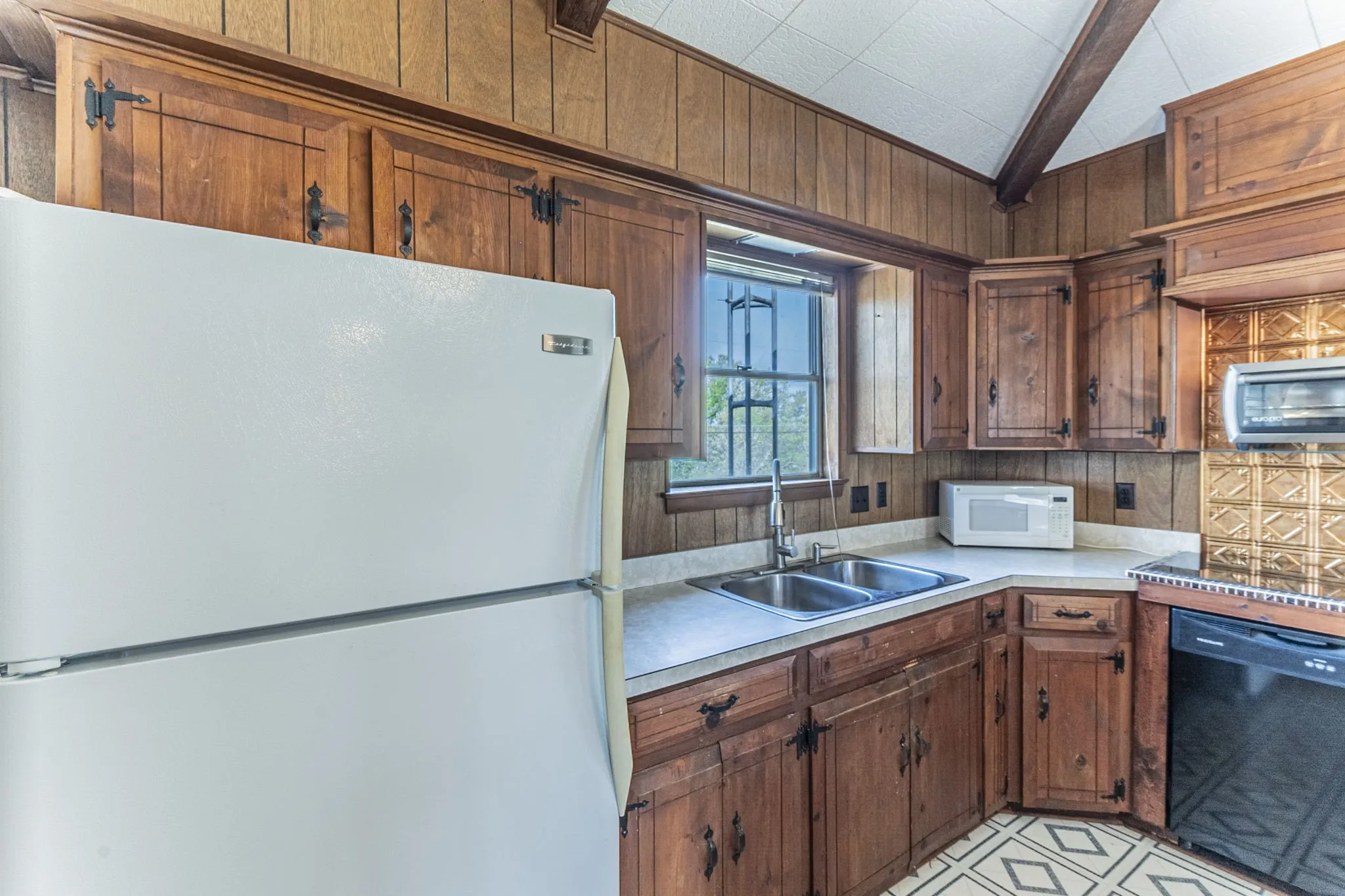 The kitchen has plenty of storage space, a cooktop, dishwasher, small convection oven and microwave. Refrigerator remains with property. You have a lovely view from the kitchen sink!