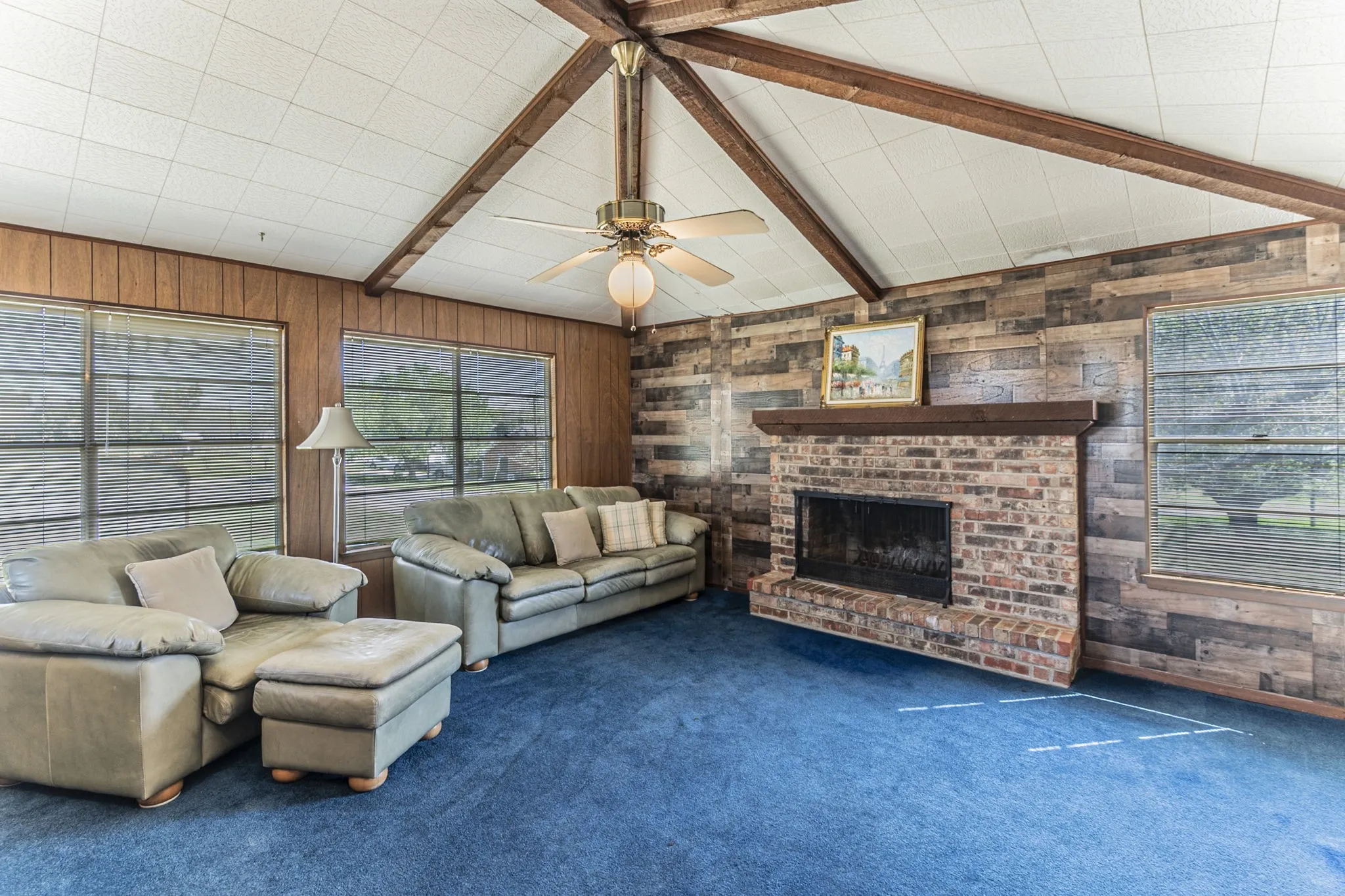Another view of the upstairs living room with windows everywhere for your hilltop views! The fireplace includes a wood mantel and brick hearth.