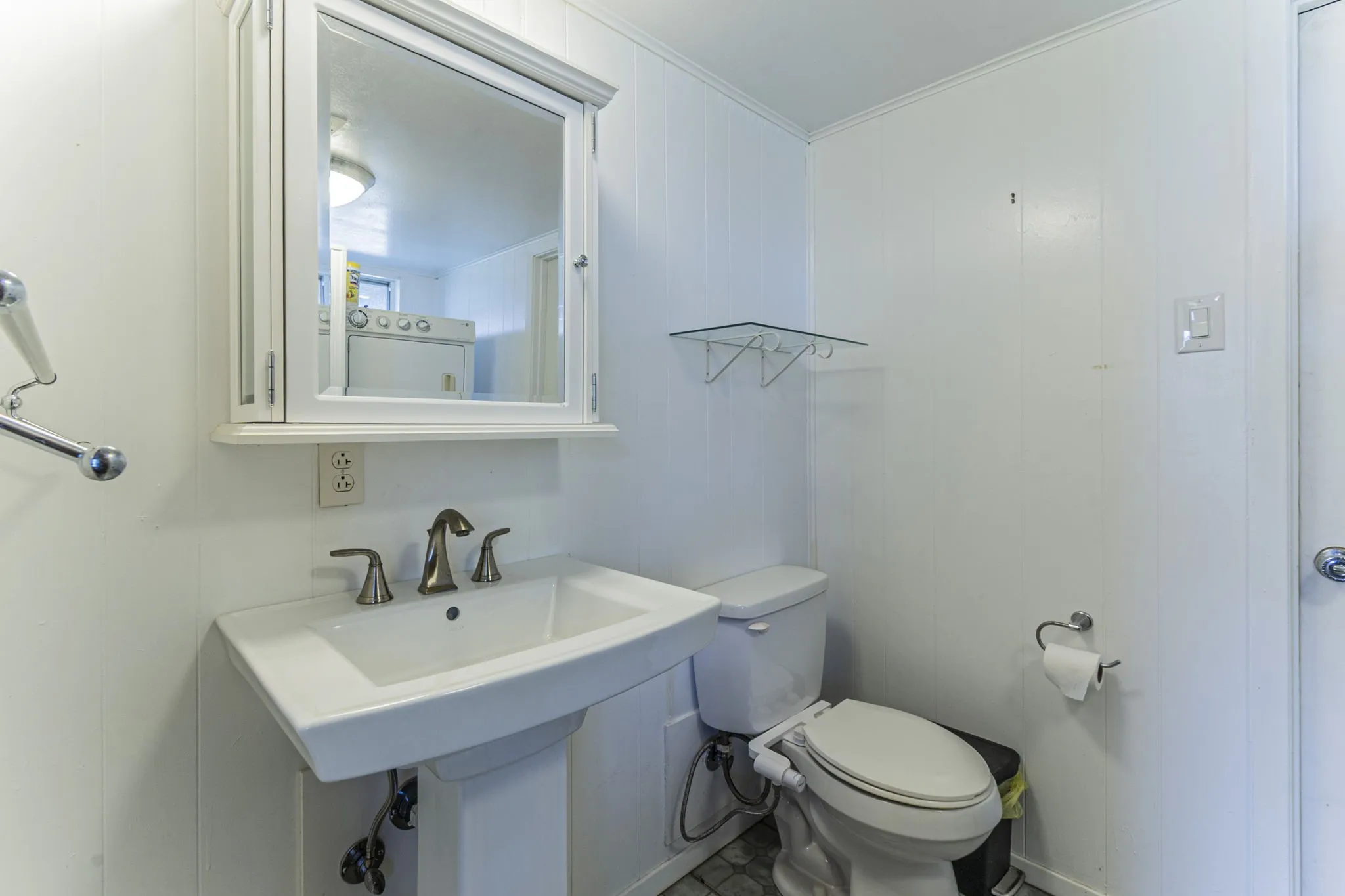 The downstairs bathroom with pedestal sink, updated commode, and medicine cabinet.