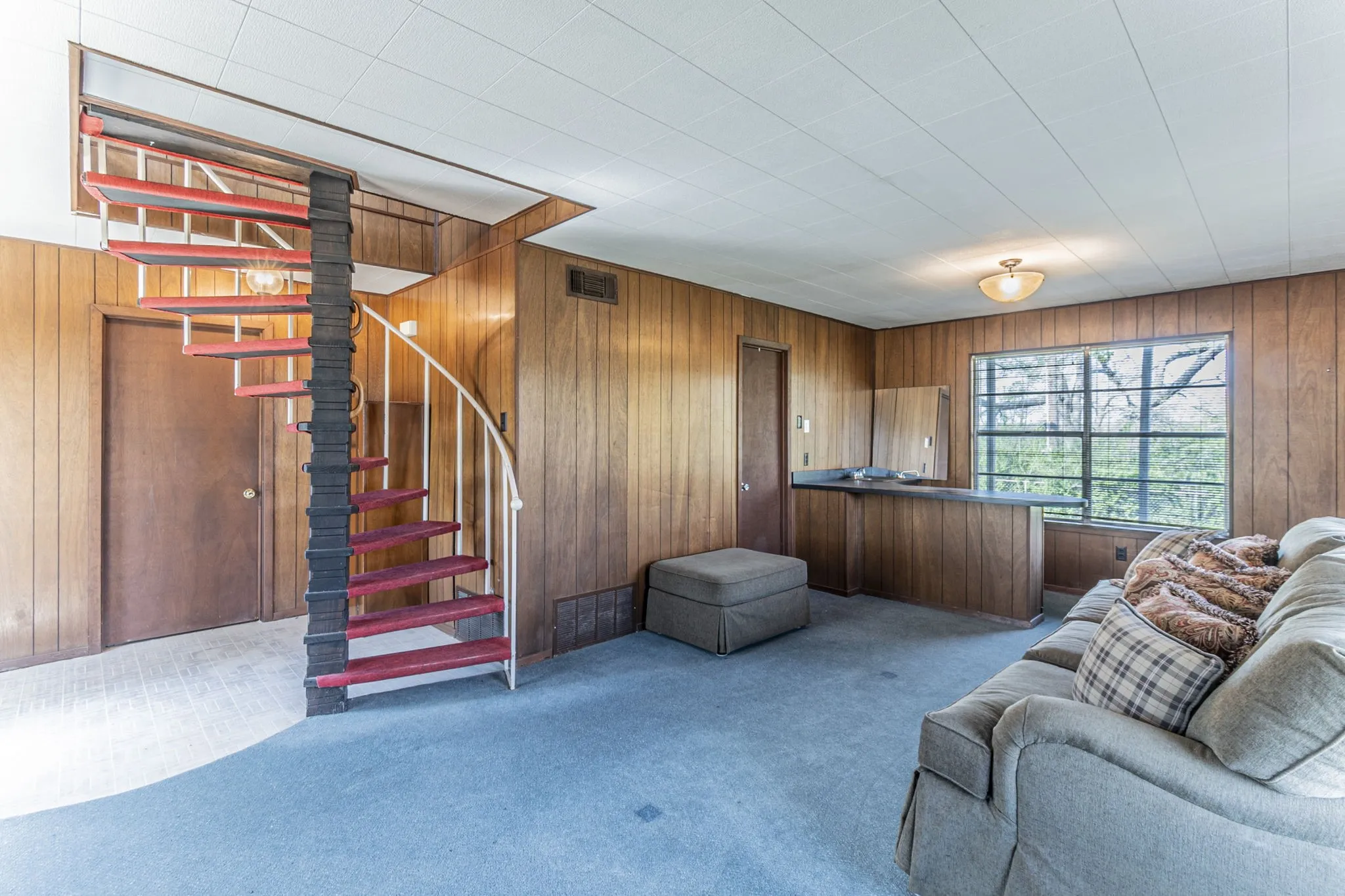 As you enter the home, this is the downstairs living room with a wet bar in the rear of this photo. The spiral staircase leads up to the larger part of the home. Doorway to the left leads to the garage. Doorway at rear is the 2nd bathroom.