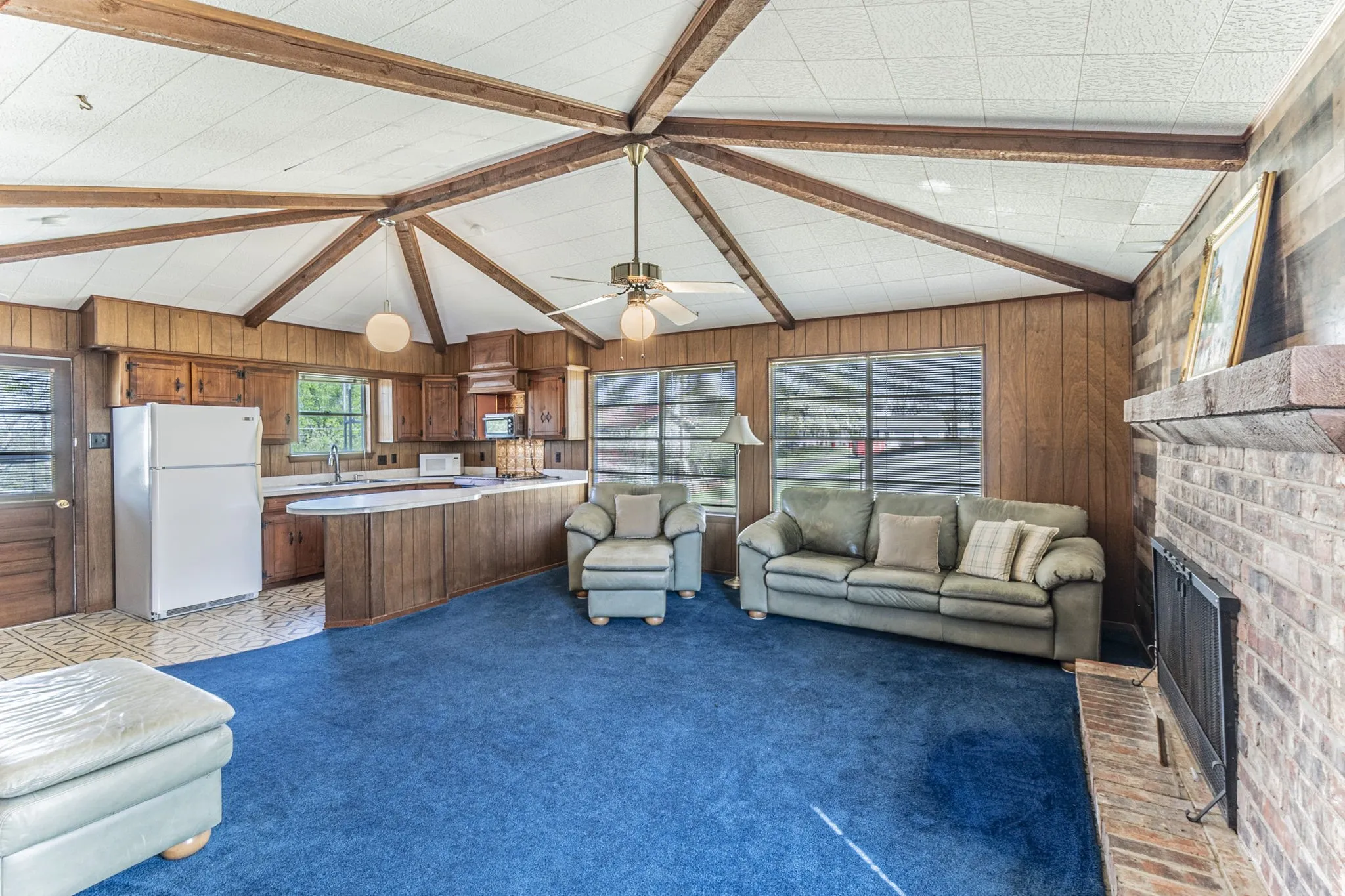 The upstairs living room has paneled walls, a beamed ceiling, and wood-burning fireplace.