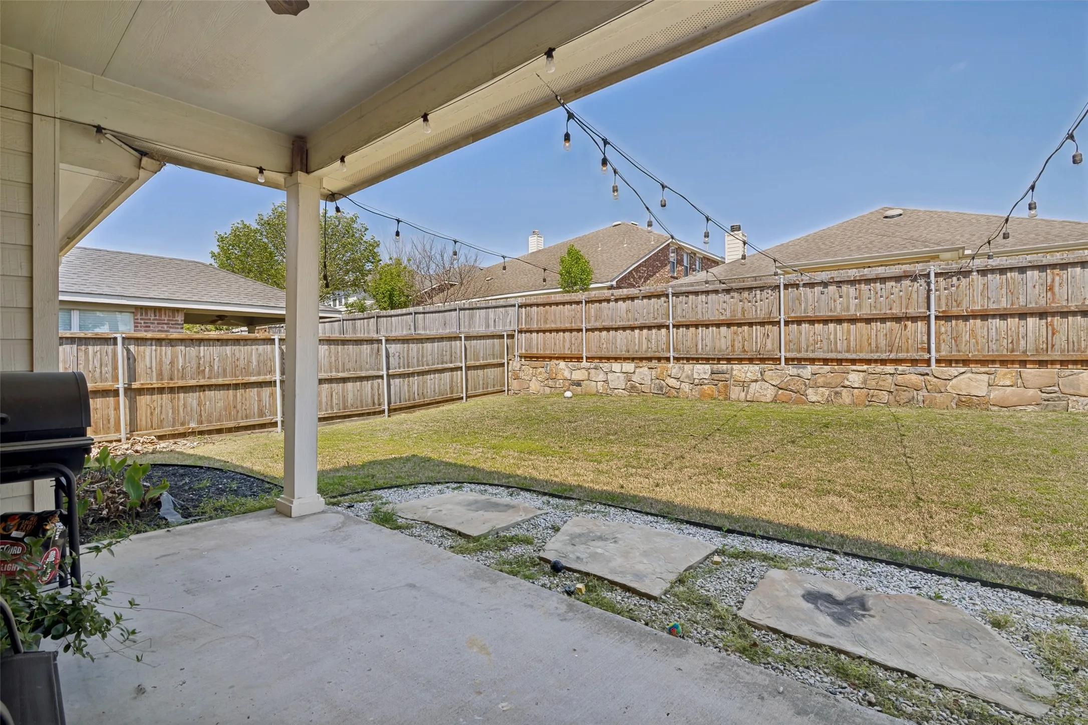 Covered backyard patio provides space for relaxing and grilling.