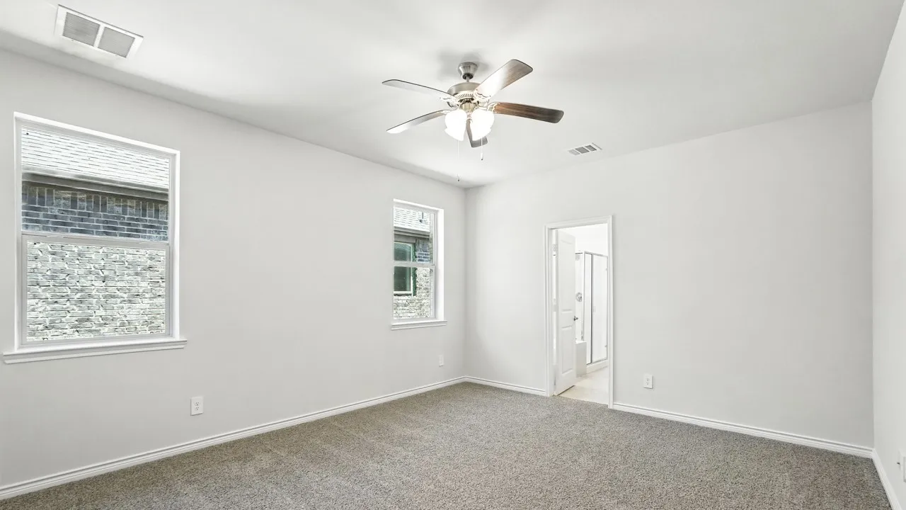 Carpeted spare room with a ceiling fan and baseboards