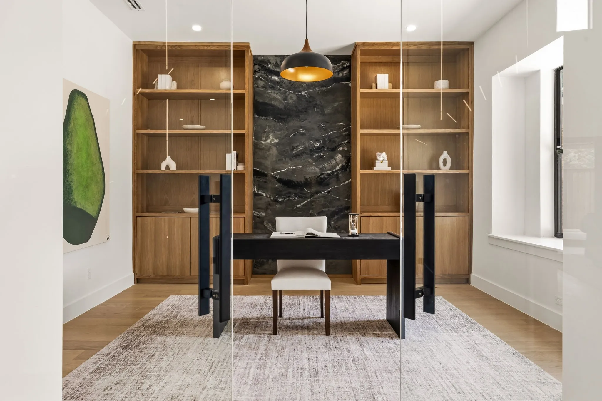 Dedicated office space featuring a built-in wood-finish shelving system, dark stone-finish accent wall, and wood-finish flooring