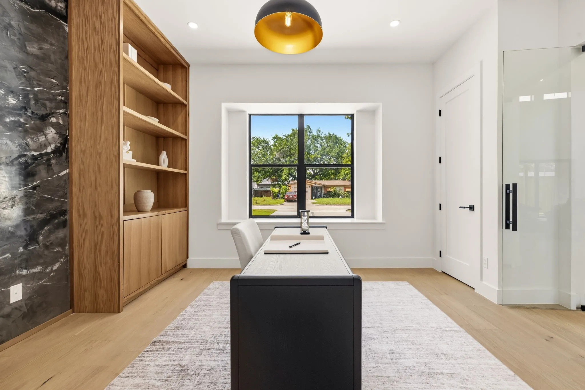 Built-in wood shelving with lower cabinetry, a dark accent wall, and wood-finish flooring
