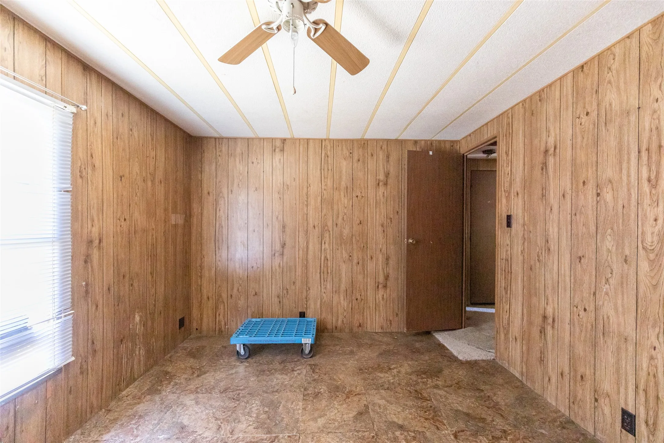 Interior room featuring wood-panel walls, vinyl flooring, and a ceiling fan