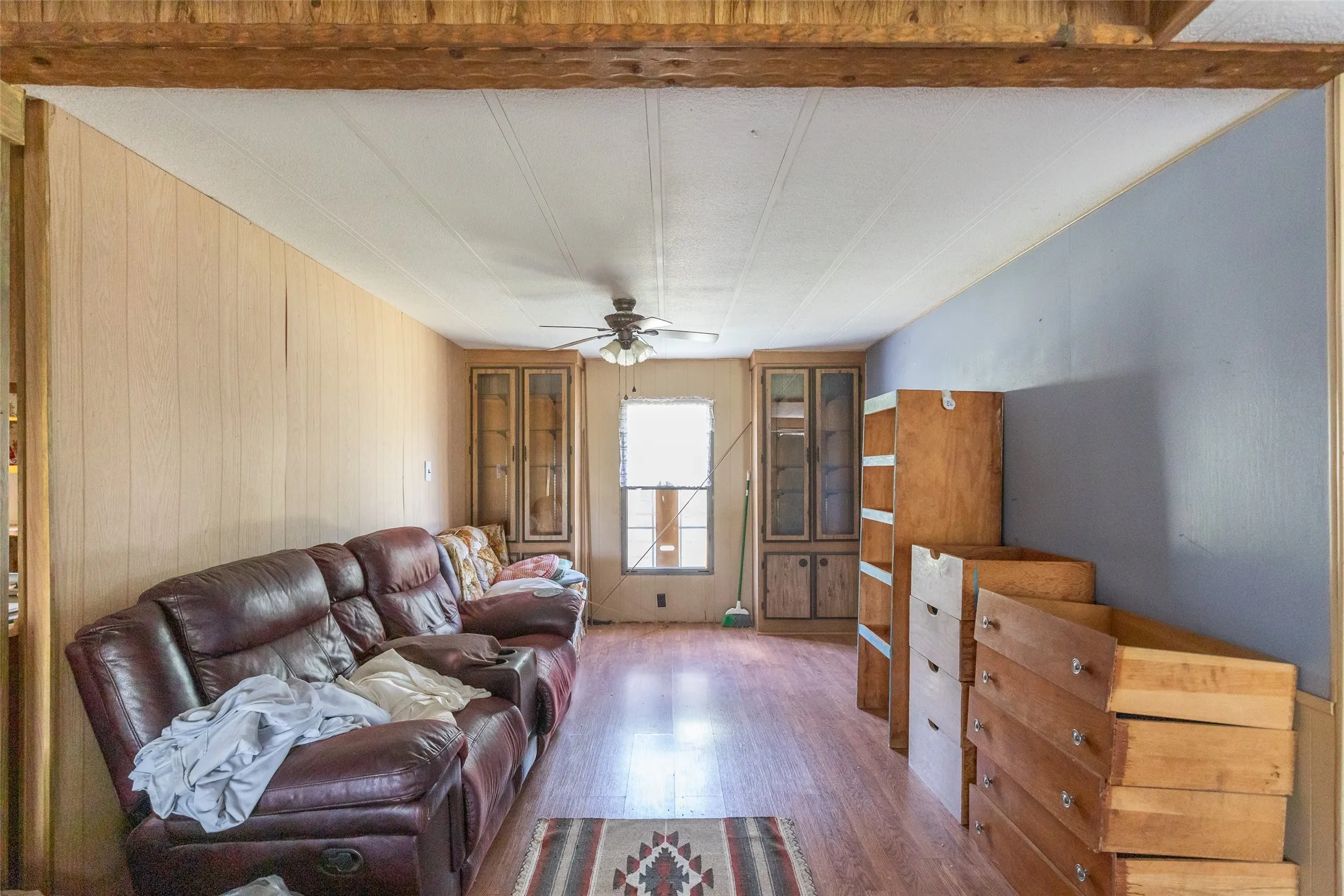 Interior space featuring wood-finish flooring, paneled walls, and a ceiling fan
