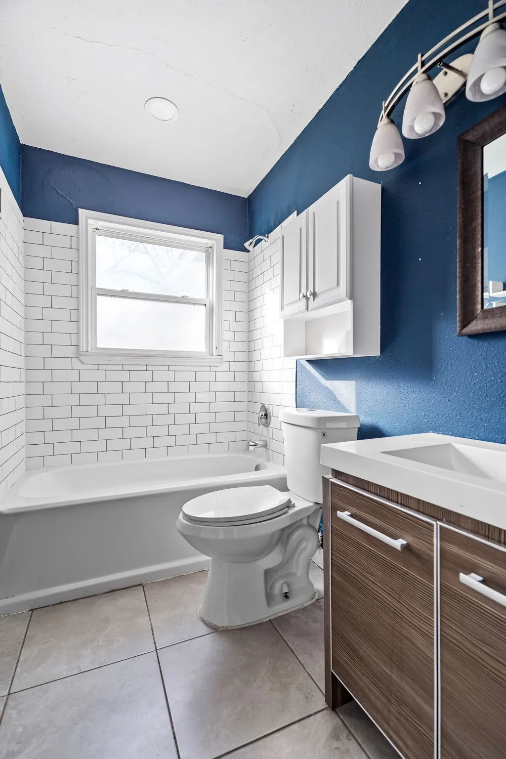 Full bathroom featuring tile patterned flooring, vanity, toilet, and tiled shower / bath combo