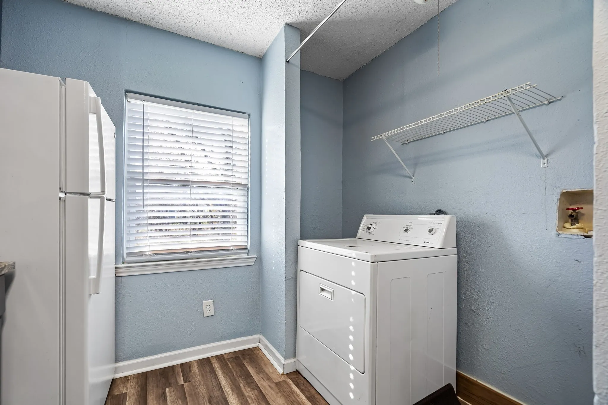 Clothes washing area featuring a textured ceiling, dark hardwood / wood-style floors, and washer / dryer