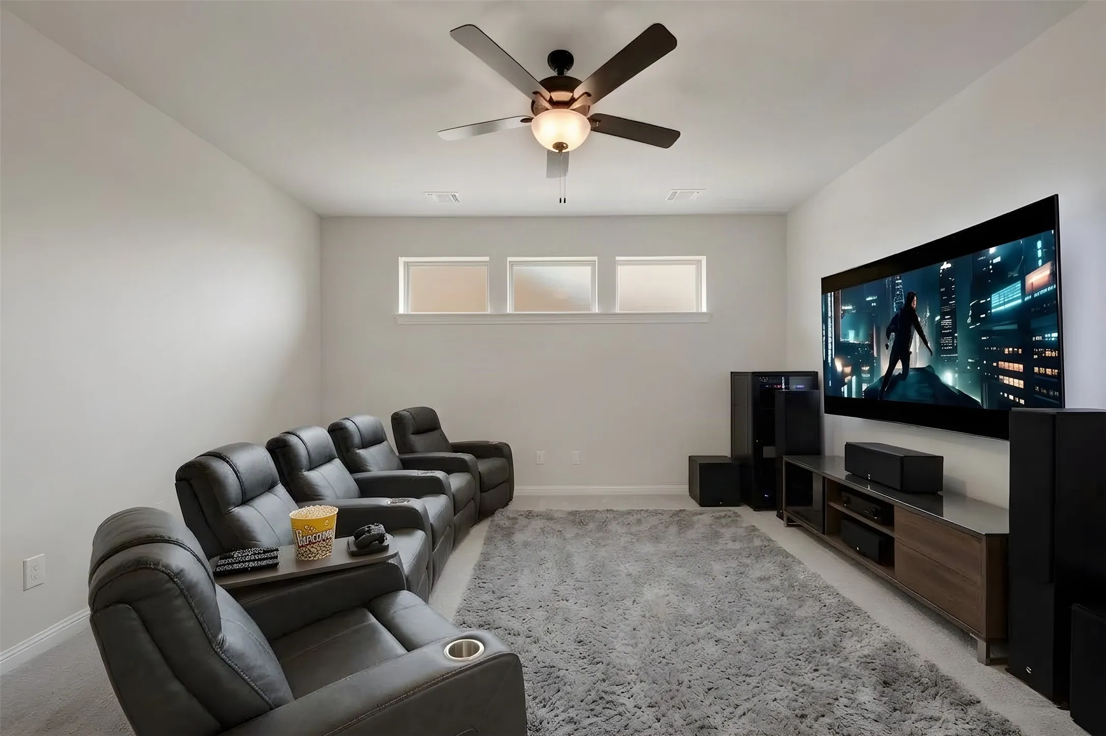 Media room featuring a ceiling fan, three horizontal transom windows, and wall-to-wall carpeting
