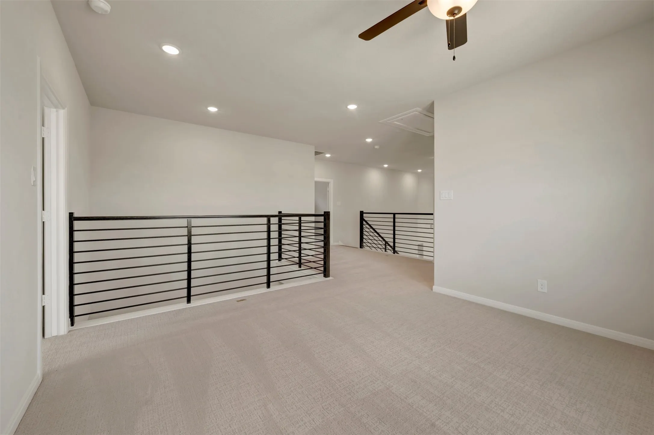 Loft space featuring carpet flooring, recessed lighting, and modern black horizontal railing