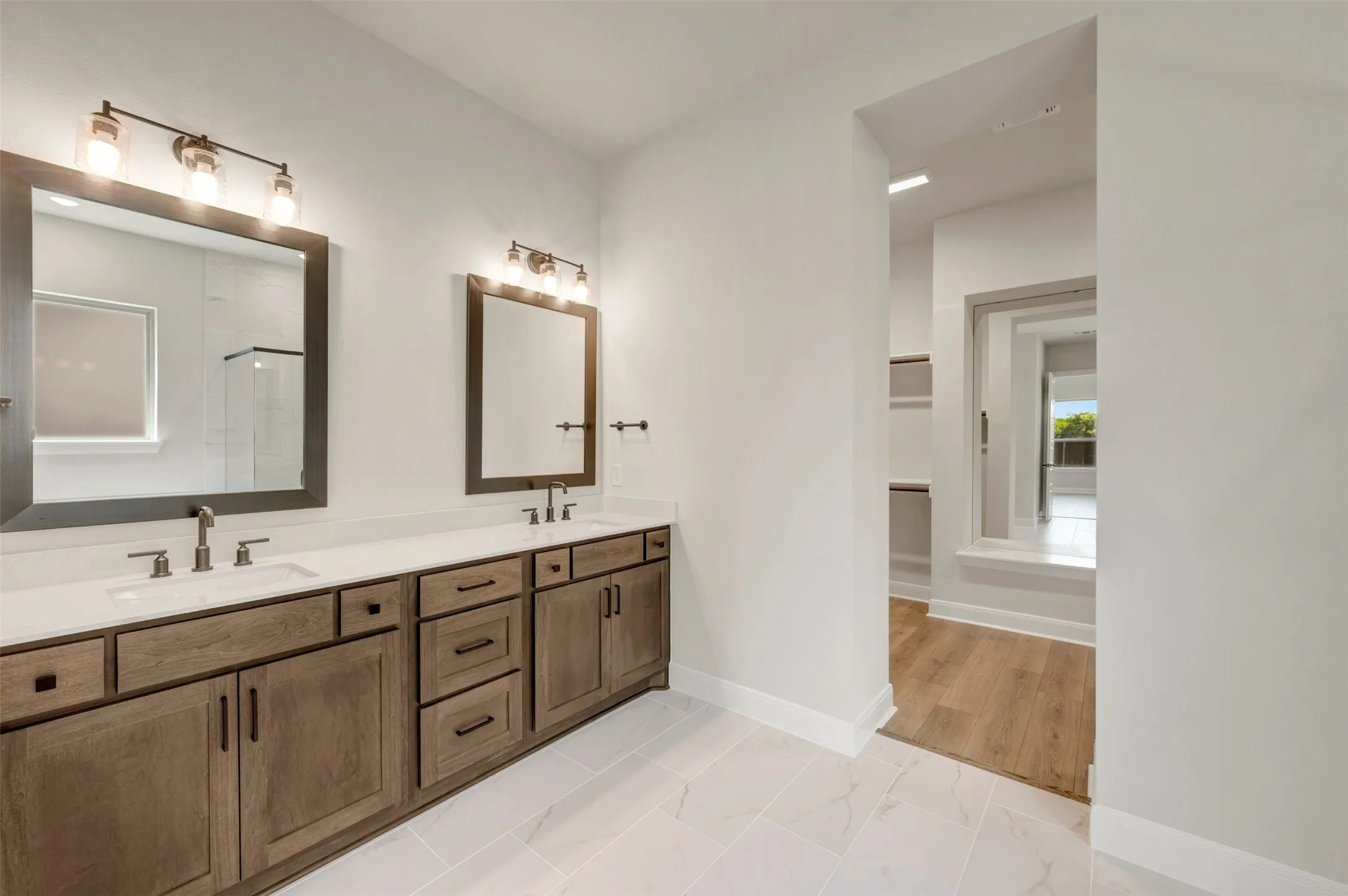 Dual vanity with wood-finish cabinetry, integrated sinks, and individual mirrors