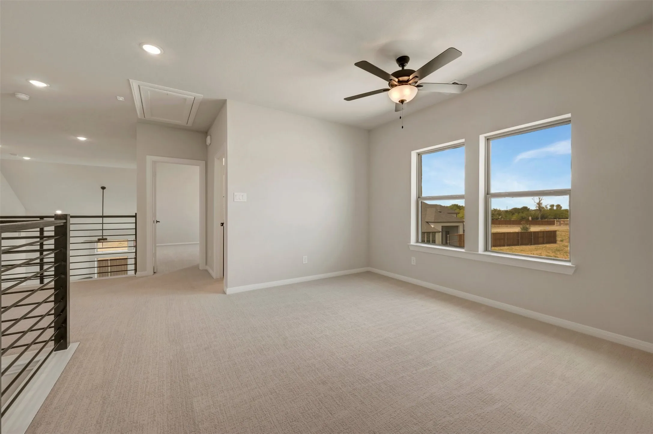 Carpeted loft space featuring two windows, a ceiling fan with integrated lighting, and recessed ceiling lights
